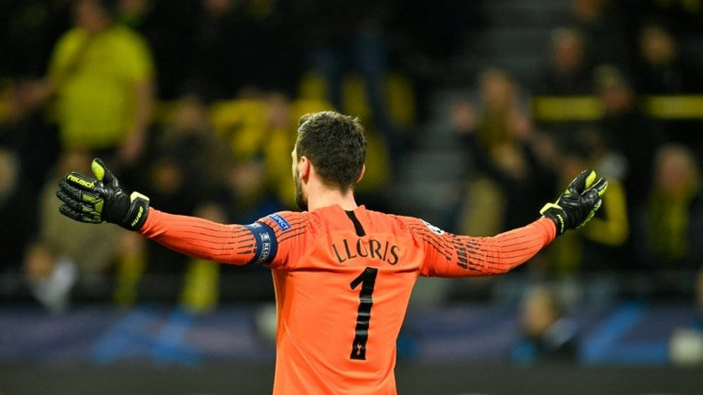足球 桌布 壁紙 — 一名身穿橙色球衣、背號1號、名字LLORIS的足球守門員，在夜晚面對模糊的球場人群，張開雙臂站立。