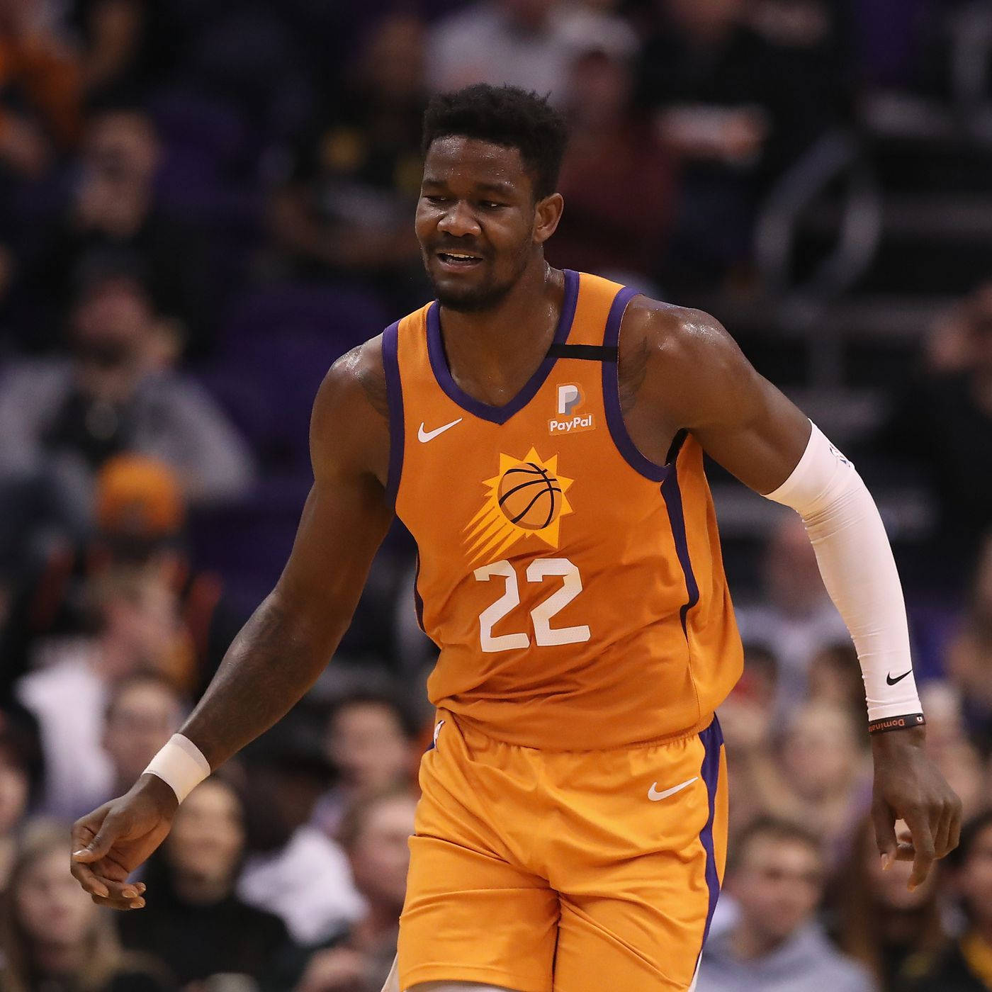 NBA 桌布 壁紙 — 一名身穿橙色球衣、號碼22的籃球運動員在比賽中微笑，身後是模糊的人群。