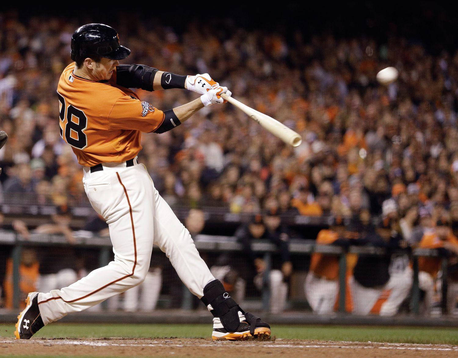 Posey 桌布 壁紙 — 一名身穿橙色球衣的棒球選手在球場燈光下揮棒擊球，背景是模糊的人群。