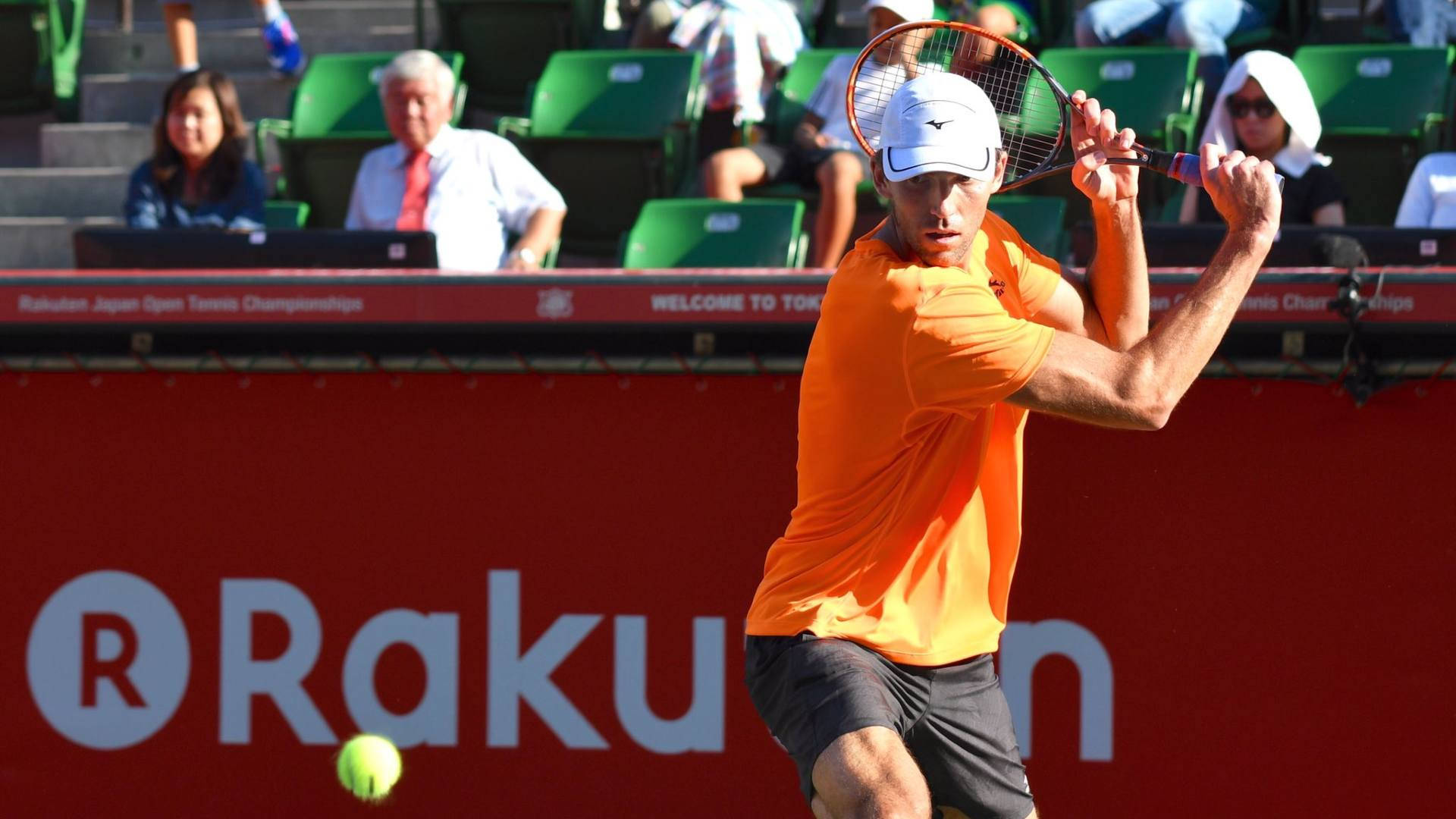 網球 桌布 壁紙 — 一名身穿橙色球衣的男網球選手在樂天日本公開賽中揮拍擊打綠色網球。