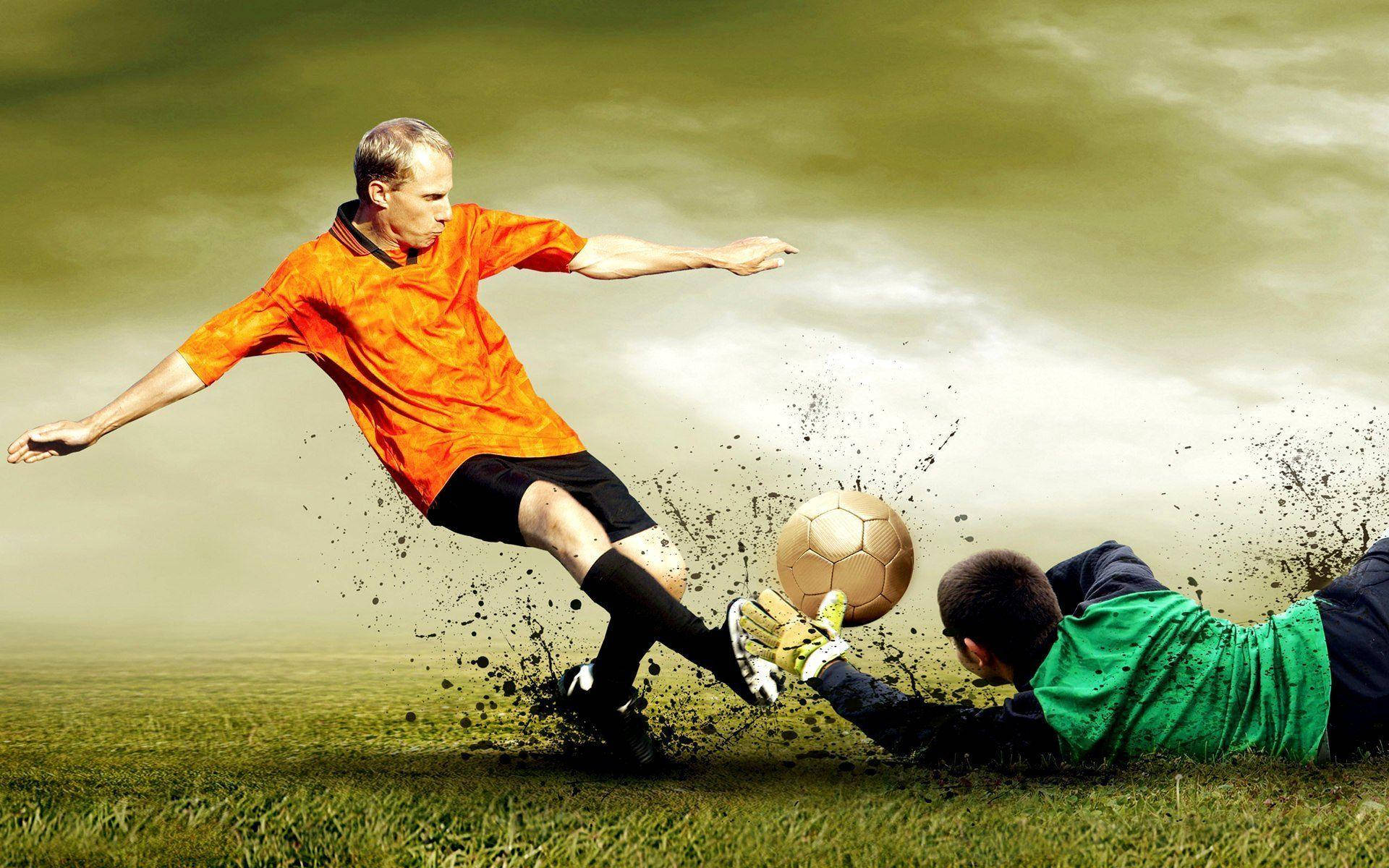 HD Sports 桌布 壁紙 — 一名身穿橙色球衣的足球員踢球，而身穿綠色球衣的守門員在草地上飛身撲救。