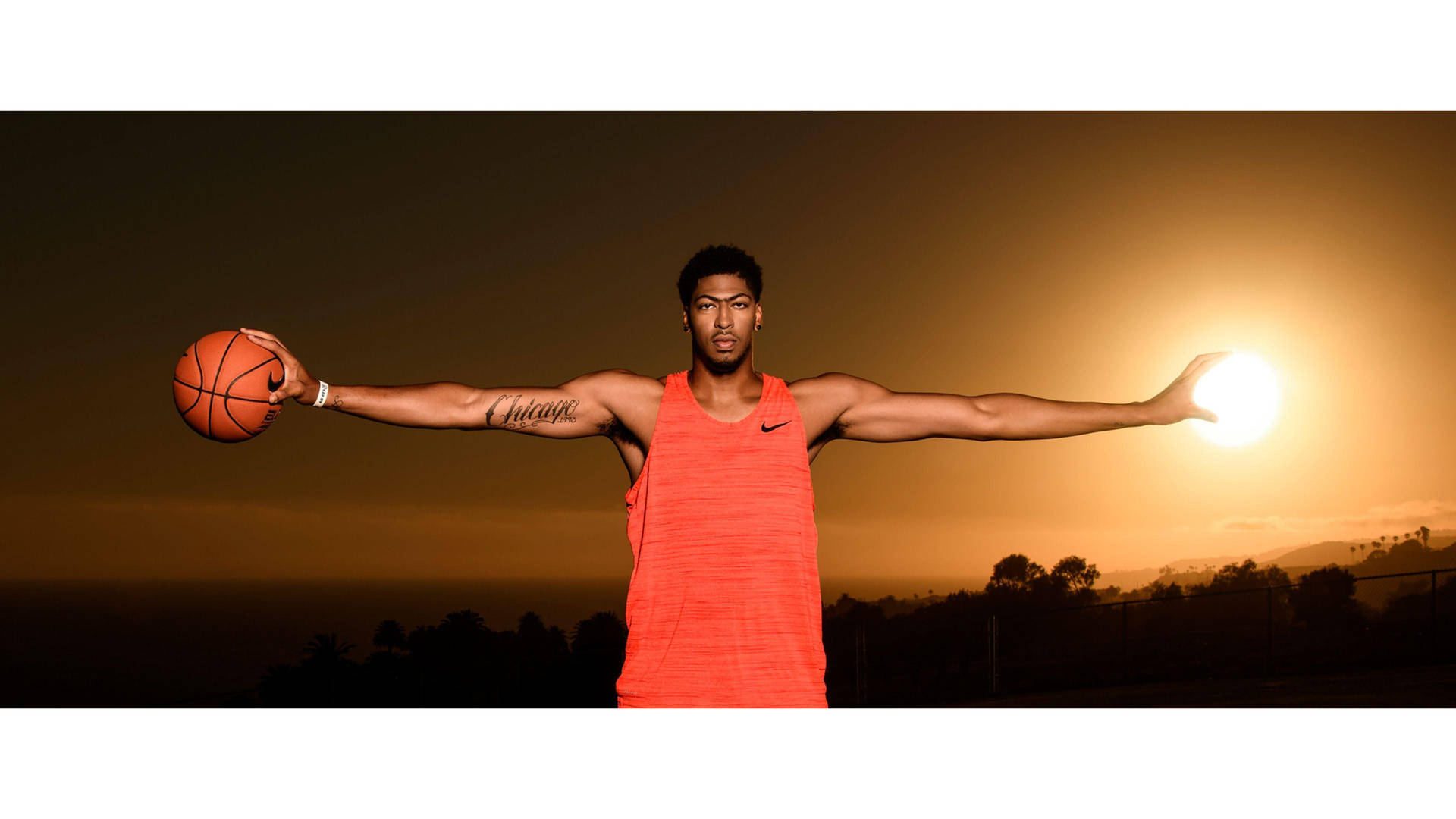 運動型男子在日落時分雙臂伸展手持籃球。 — Michael B Jordan 壁紙