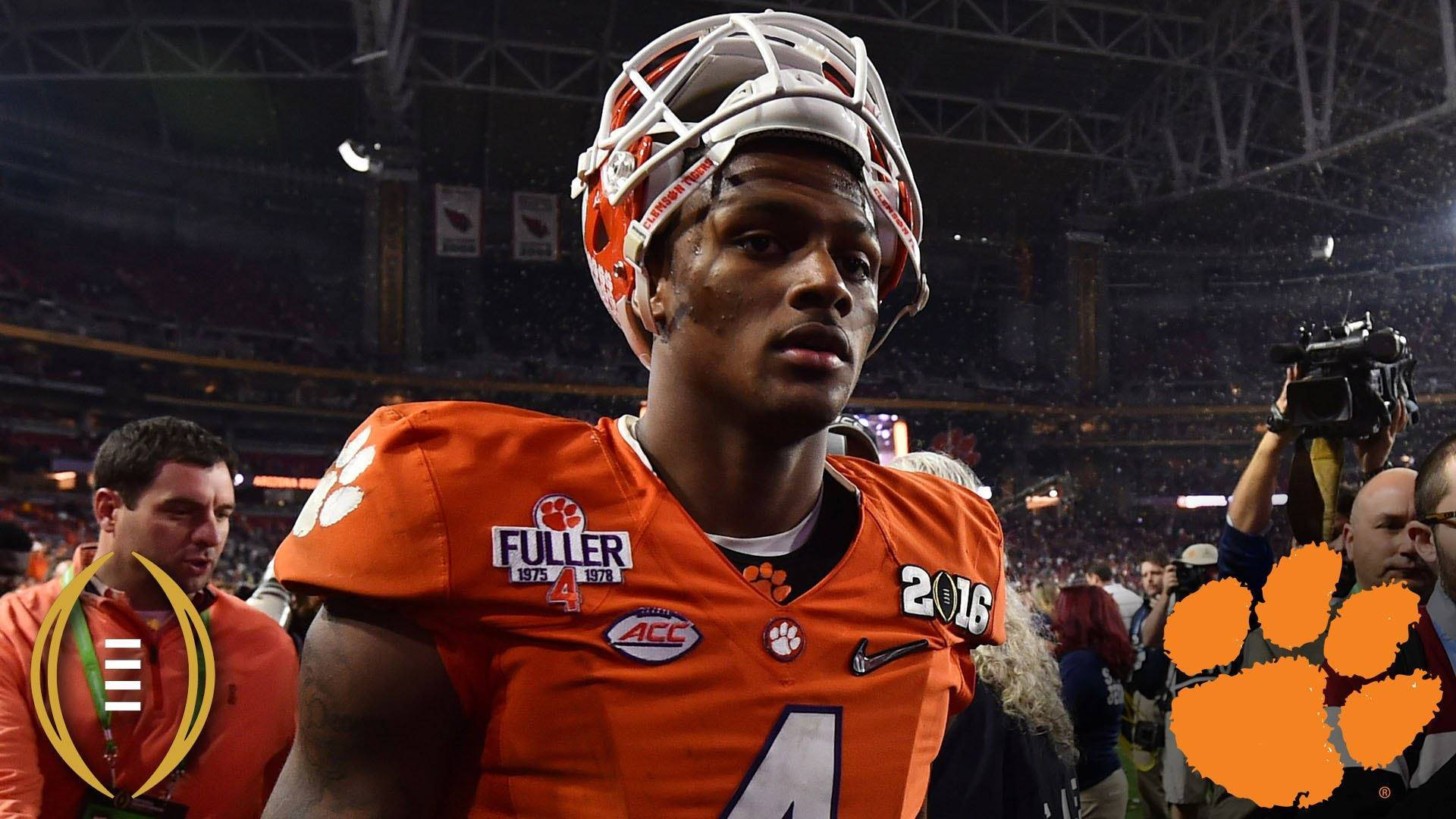 Deshaun Watson 桌布 壁紙 — 一名身穿橙色裝備的克萊姆森足球員在體育場燈光下專注站立，周圍有群眾和攝製組。