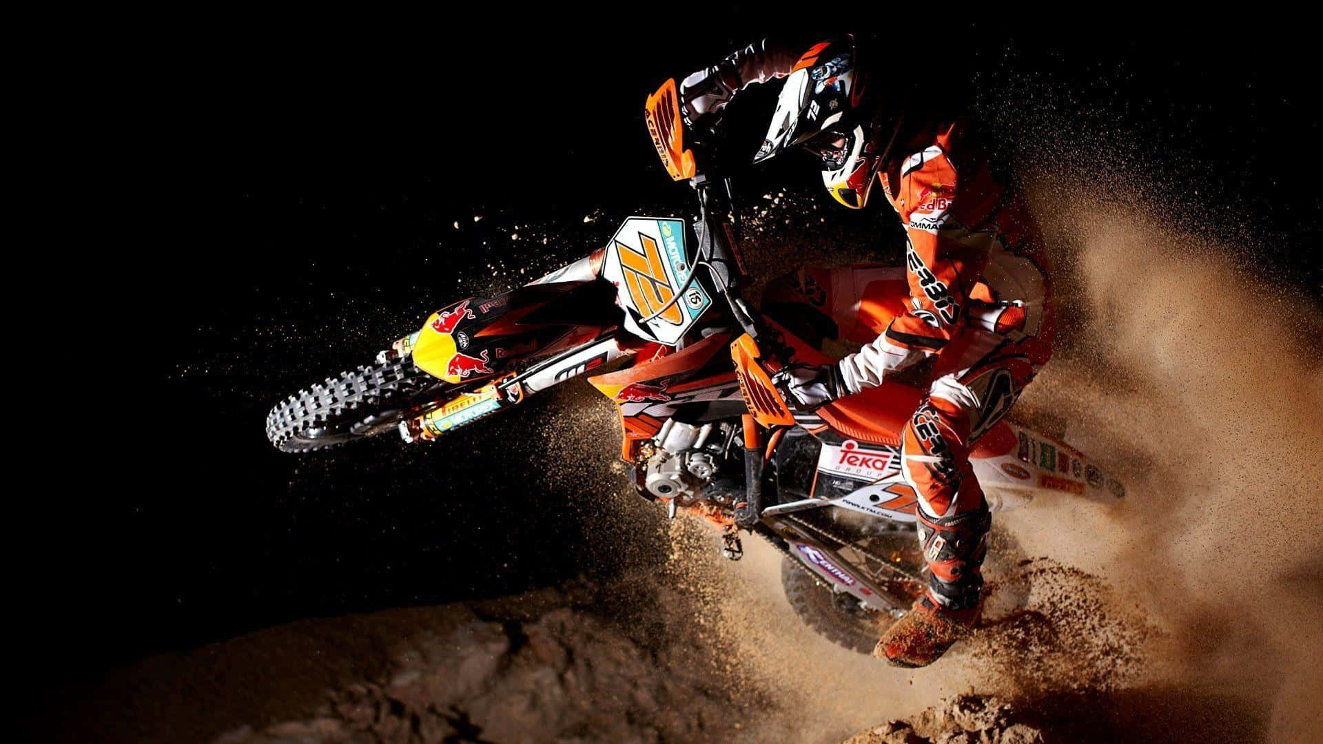 Motocross 桌布 壁紙 — 一名身穿橙色裝備的越野摩托車手在黑色背景下，駕駛越野摩托車急轉彎，揚起塵土。