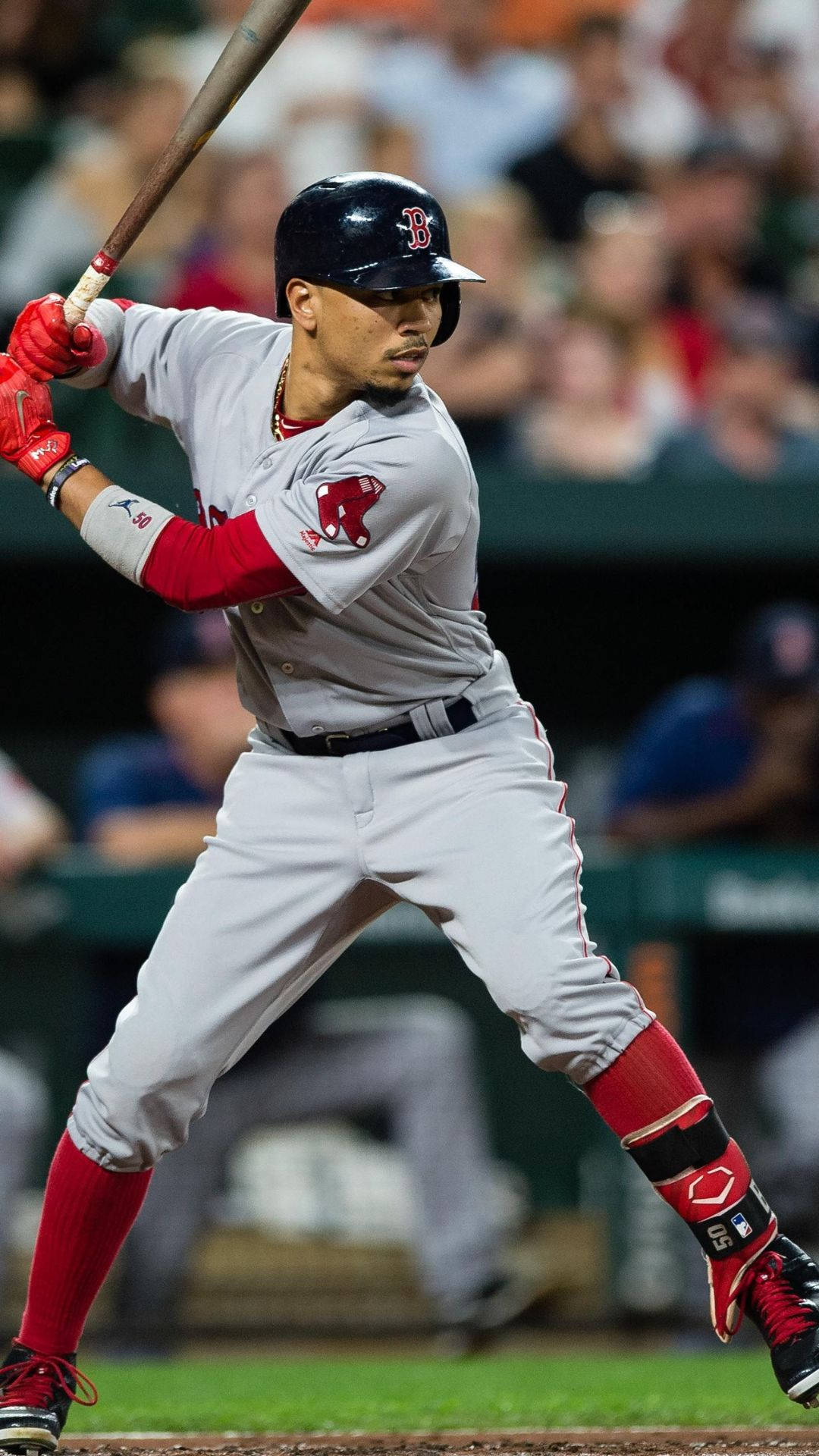 Mookie Betts 桌布 壁紙 — 一名身穿波士頓紅襪隊球衣的棒球選手，在夜間比賽的球場燈光下，專注地揮棒。