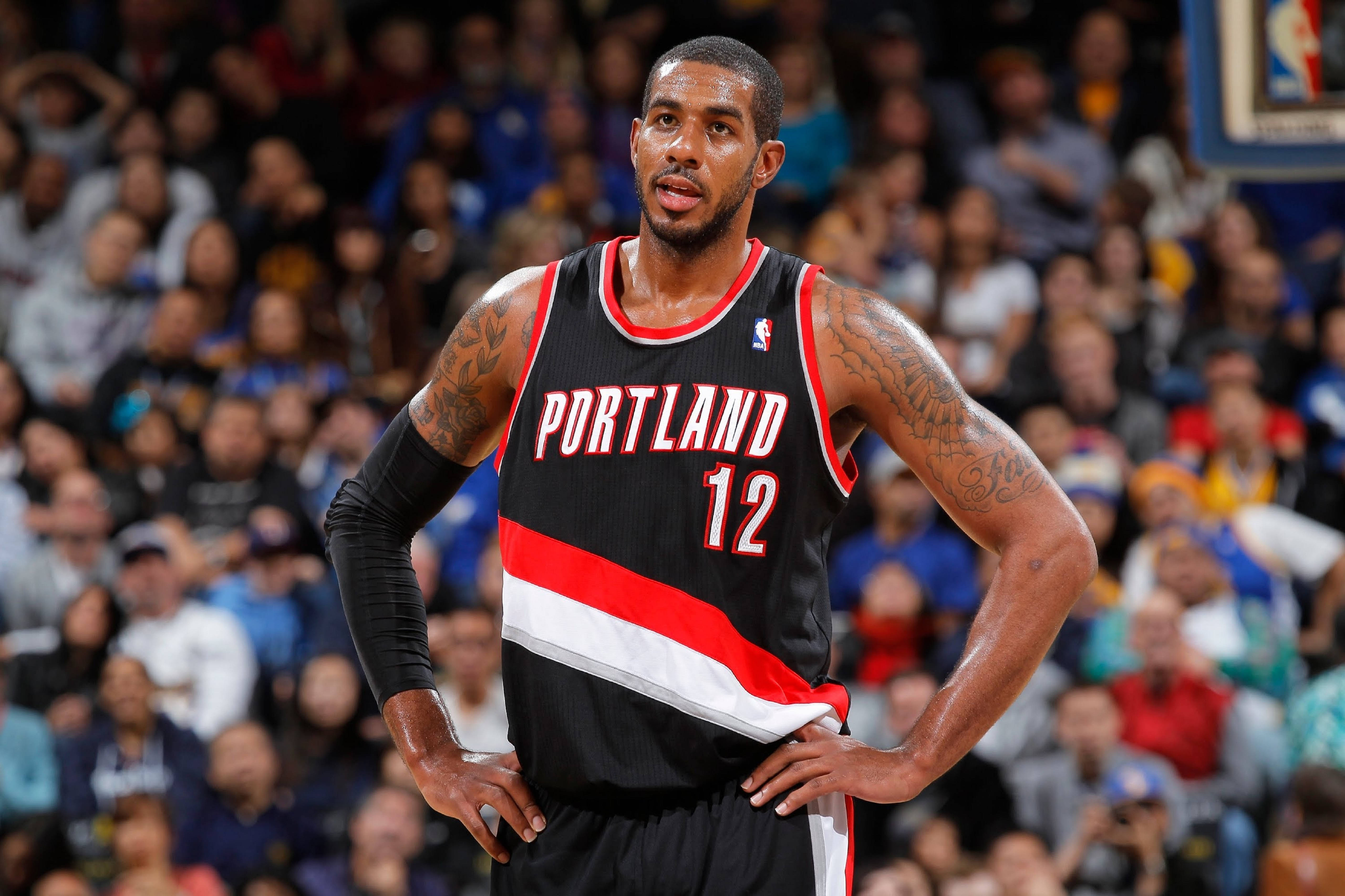 Lamarcus Aldridge 桌布 壁紙 — 一名身穿波特蘭拓荒者球衣的籃球運動員在比賽中自信地雙手叉腰站立，身後是模糊的人群。