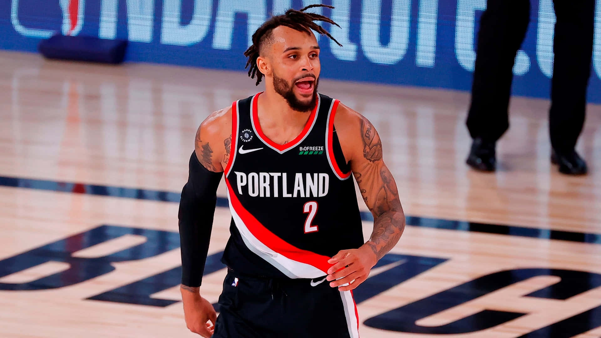 NBA 桌布 壁紙 — 一名身穿波特蘭拓荒者球衣的籃球運動員在比賽中於拋光硬木球場上激烈反應。