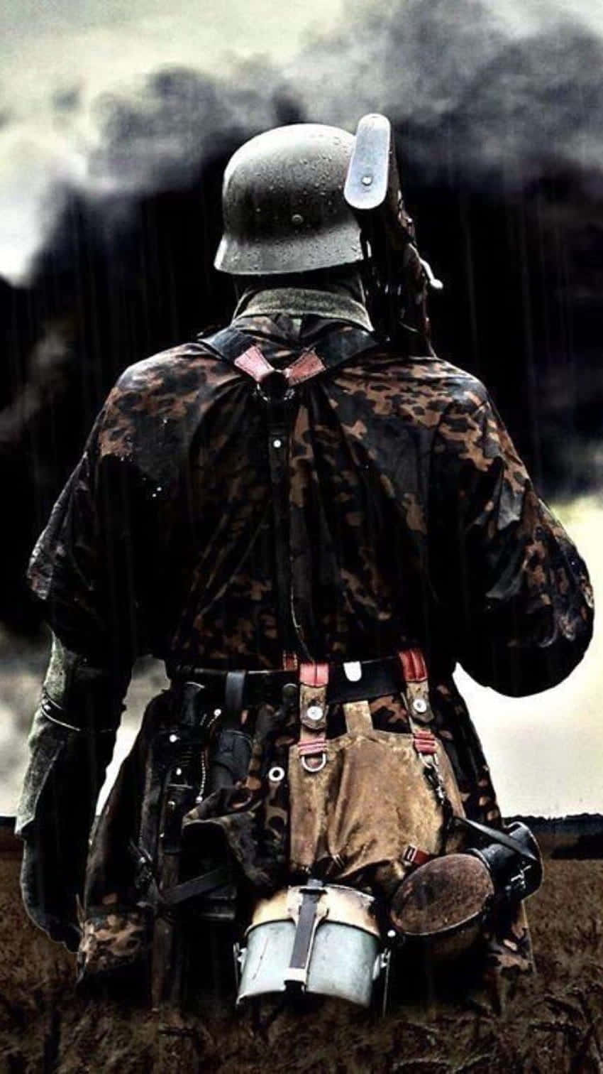 soldier 桌布 壁紙 — 一名身穿泥濘迷彩裝備和頭盔的士兵在雨中背光站立，身後有煙霧升起。