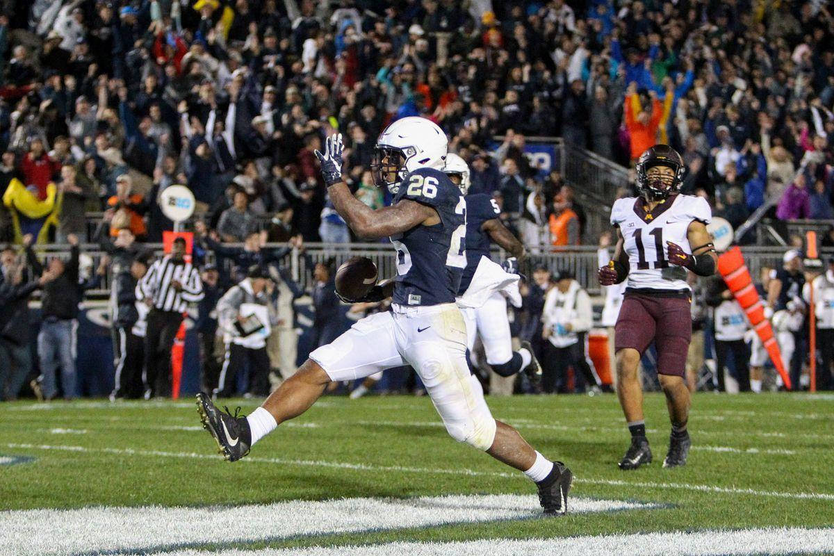 Saquon Barkley 桌布 壁紙 — 一名身穿海軍藍26號球衣的美式足球員在球場燈光下，於達陣區附近跳起接球，觀眾歡呼。