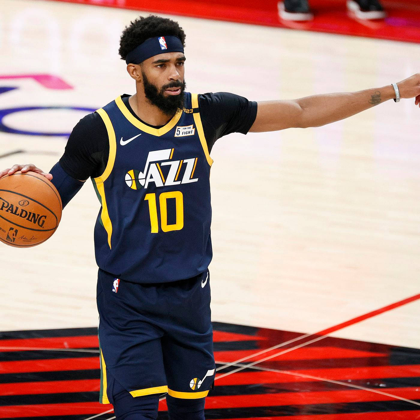 mike conley 桌布 壁紙 — 一名身穿海軍藍爵士隊球衣、背號10的籃球運動員，在帶有紅色和黑色標記的球場上運球並做手勢。