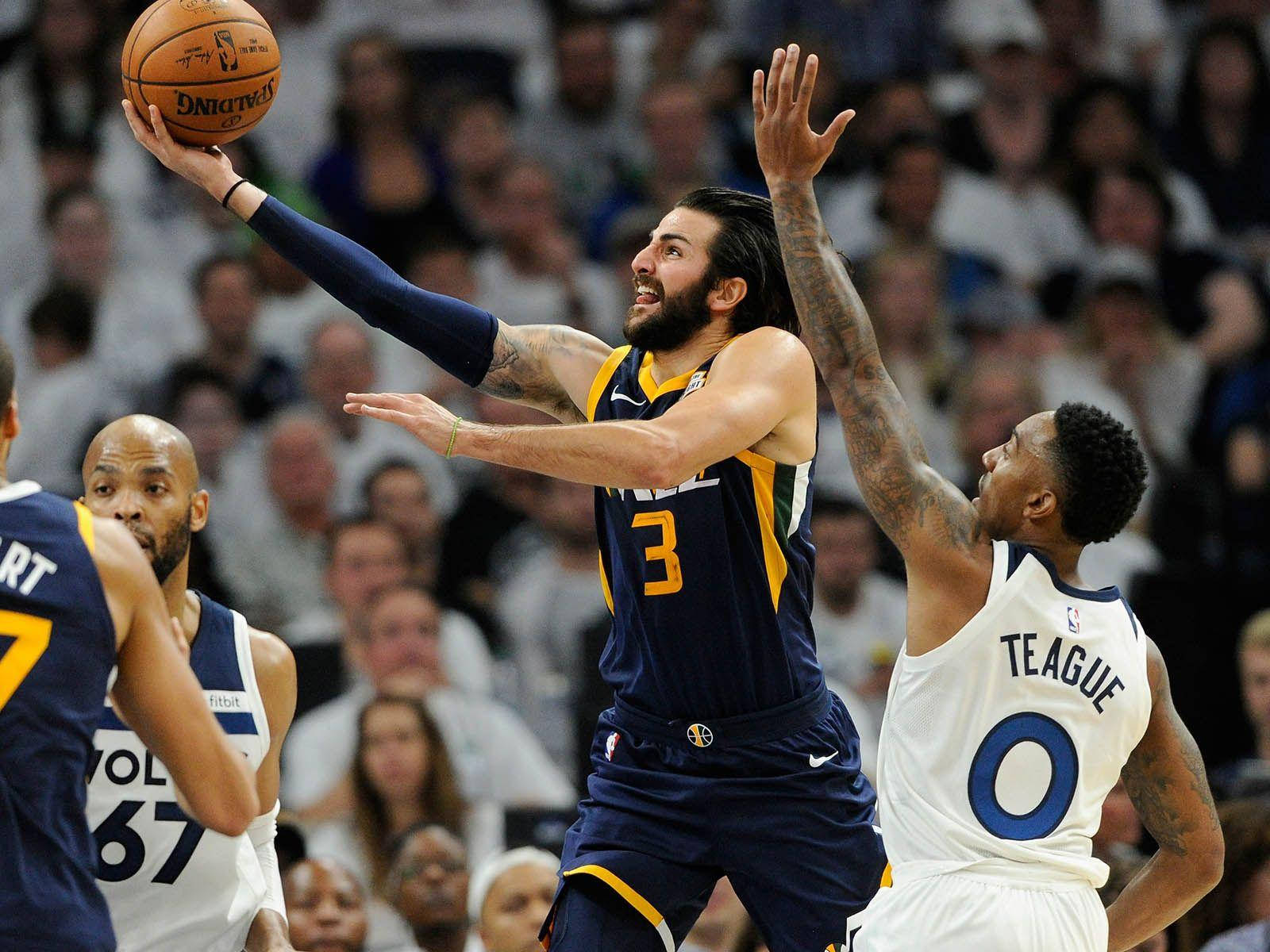 Ricky Rubio 桌布 壁紙 — 一名身穿海軍藍球衣、背號3號的籃球運動員跳起投籃，同時被一名身穿白色球衣的對手防守。