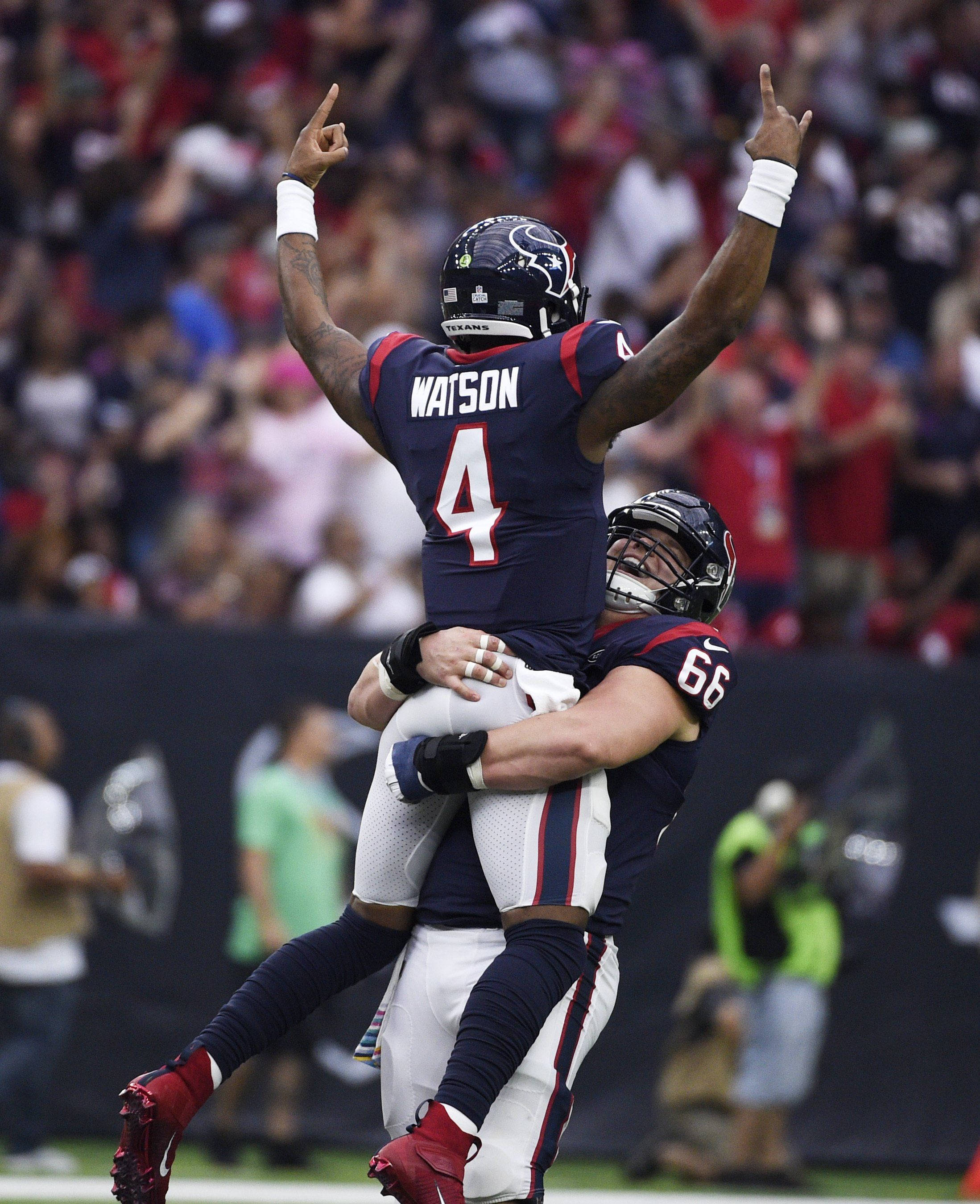 Deshaun Watson 桌布 壁紙 — 一名身穿海軍藍球衣、號碼4的美式足球員在球場上被隊友以慶祝擁抱舉起在空中。
