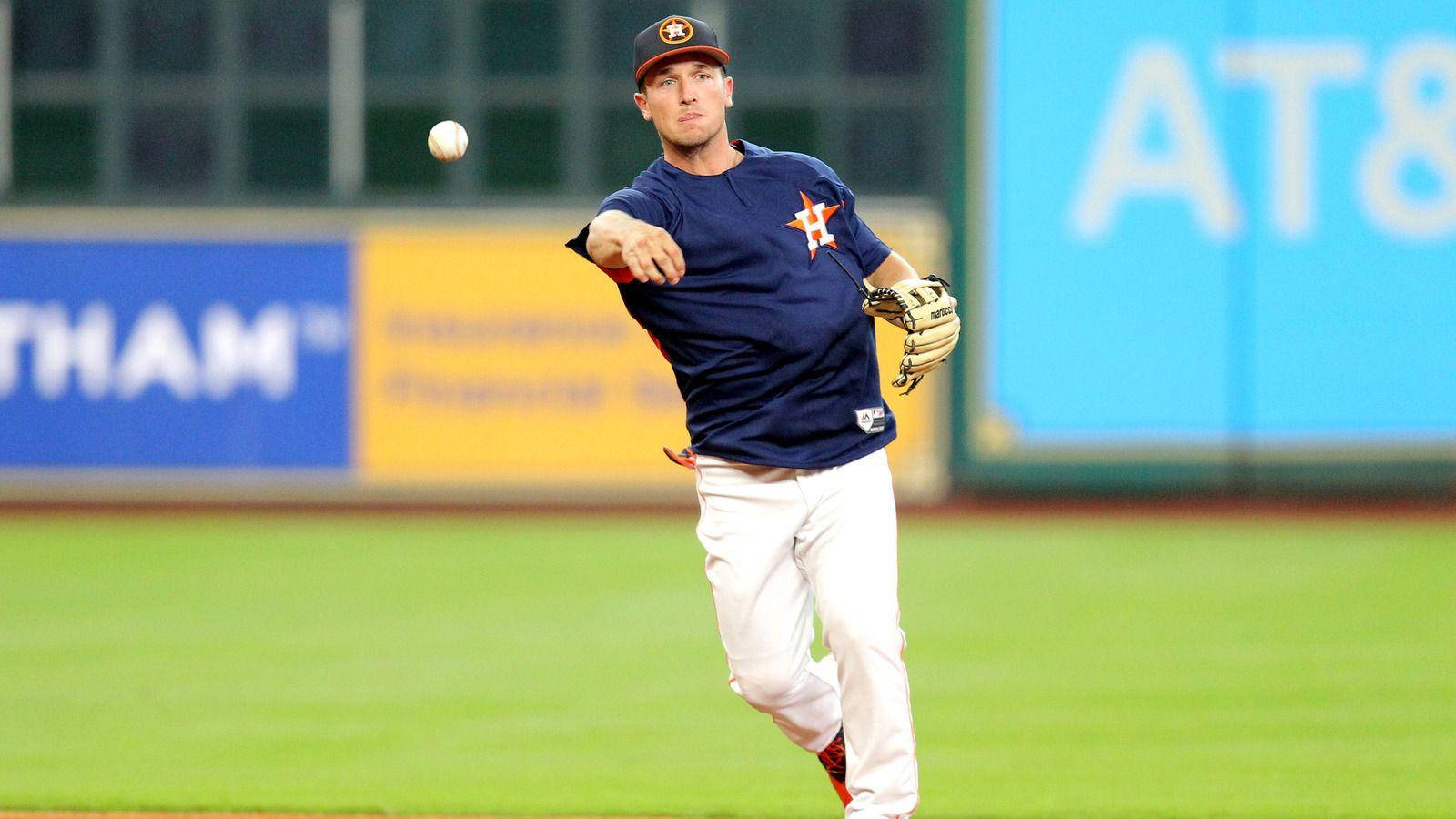 Bregman 桌布 壁紙 — 一名身穿海軍藍球衣的棒球運動員在夜間光線充足的球場上投球，背景有體育場廣告。