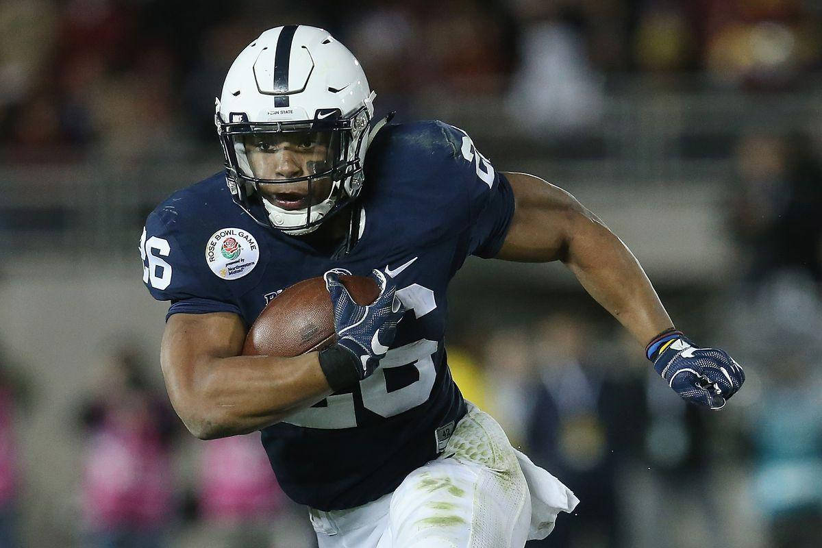 Saquon Barkley 桌布 壁紙 — 一名身穿海軍藍球衣的足球員在夜間比賽中，在球場燈光下帶球衝刺。