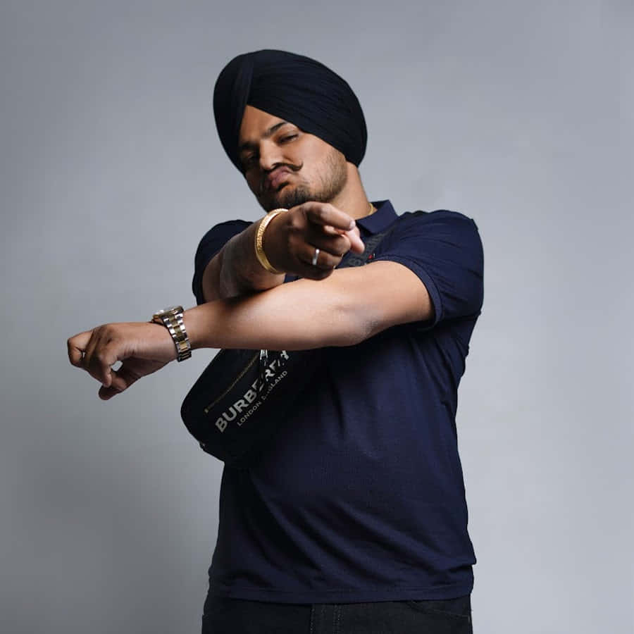 戴頭巾和金錶的男子在攝影棚自信地指著 — Sidhu Moose Wala 壁紙