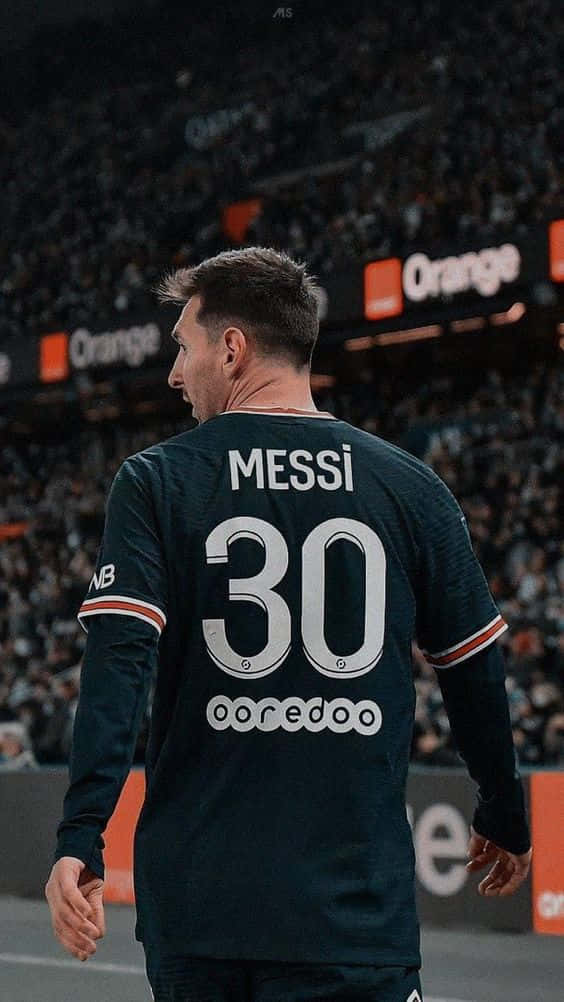 足球 桌布 壁紙 — 一名身穿深綠色球衣、印有「MESSI 30」的足球員在球場上背對鏡頭走開，背景有模糊的觀眾和橙色廣告看板。