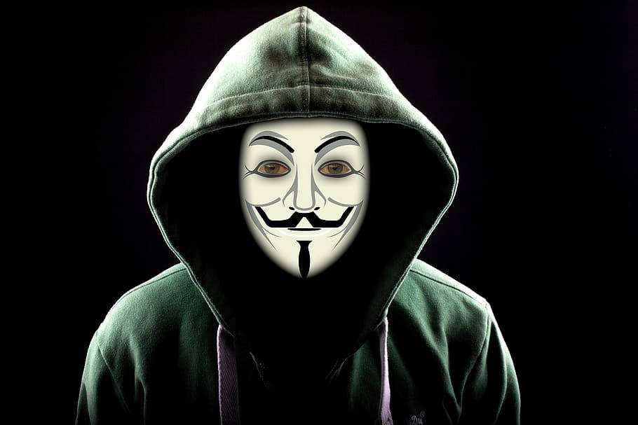 hacker 3d 桌布 壁紙 — 一名身穿深綠色連帽衫的人，在黑色背景前戴著白色蓋伊·福克斯面具。