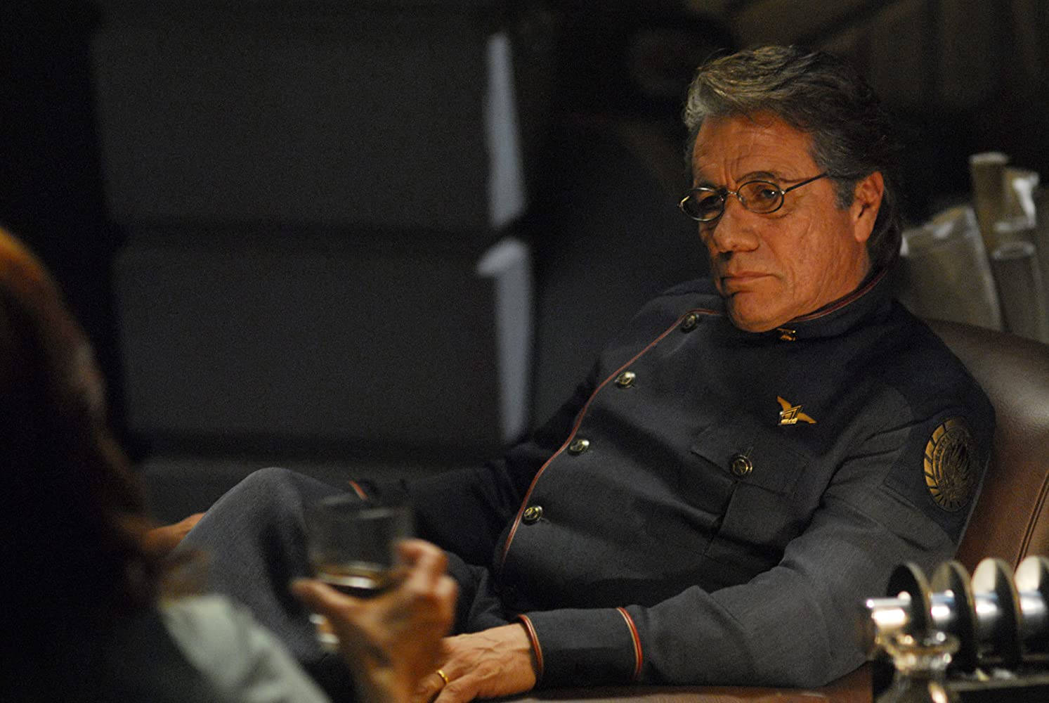 actor 桌布 壁紙 — 一名身穿深色制服、戴眼鏡的男子坐在皮椅上，在燈光昏暗的房間裡拿著一杯酒。