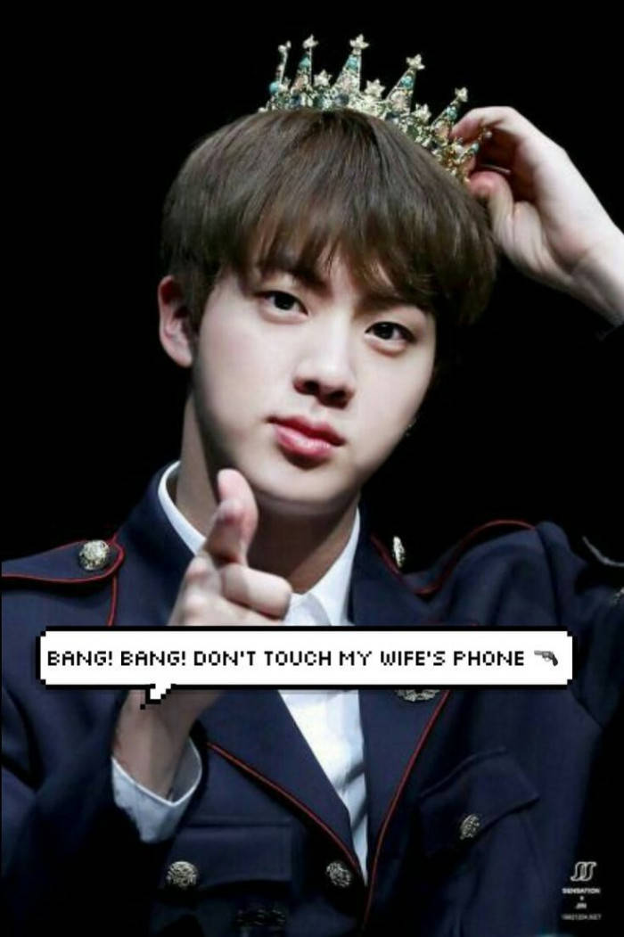 Jin 桌布 壁紙 — 一名身穿深色制服、戴著鑲有寶石皇冠的年輕男子，手持自己的皇冠，直接指向觀看者。
