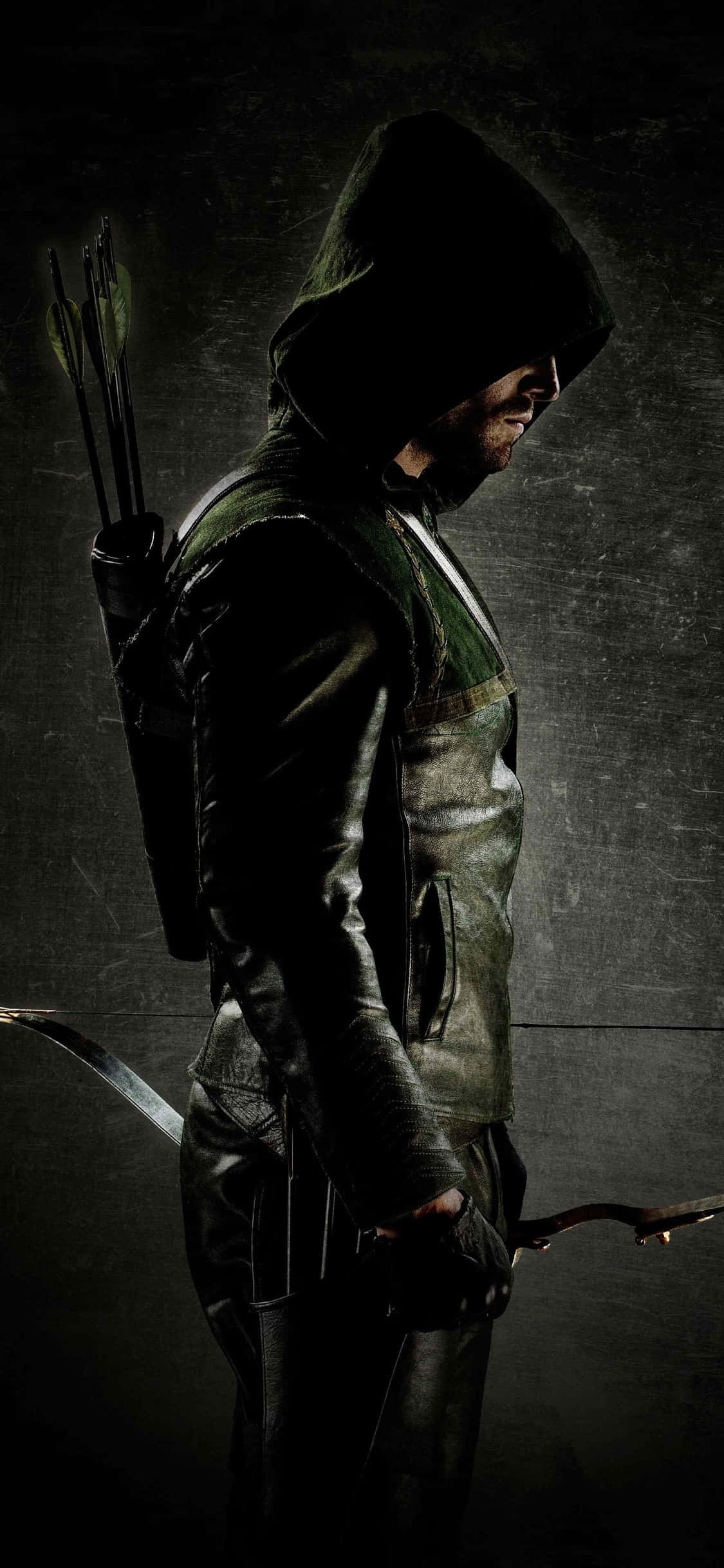 Green Arrow iPhone 桌布 壁紙 — 一名身穿深色皮革的兜帽弓箭手，手持弓和箭袋，背景是粗糙的紋理牆壁。