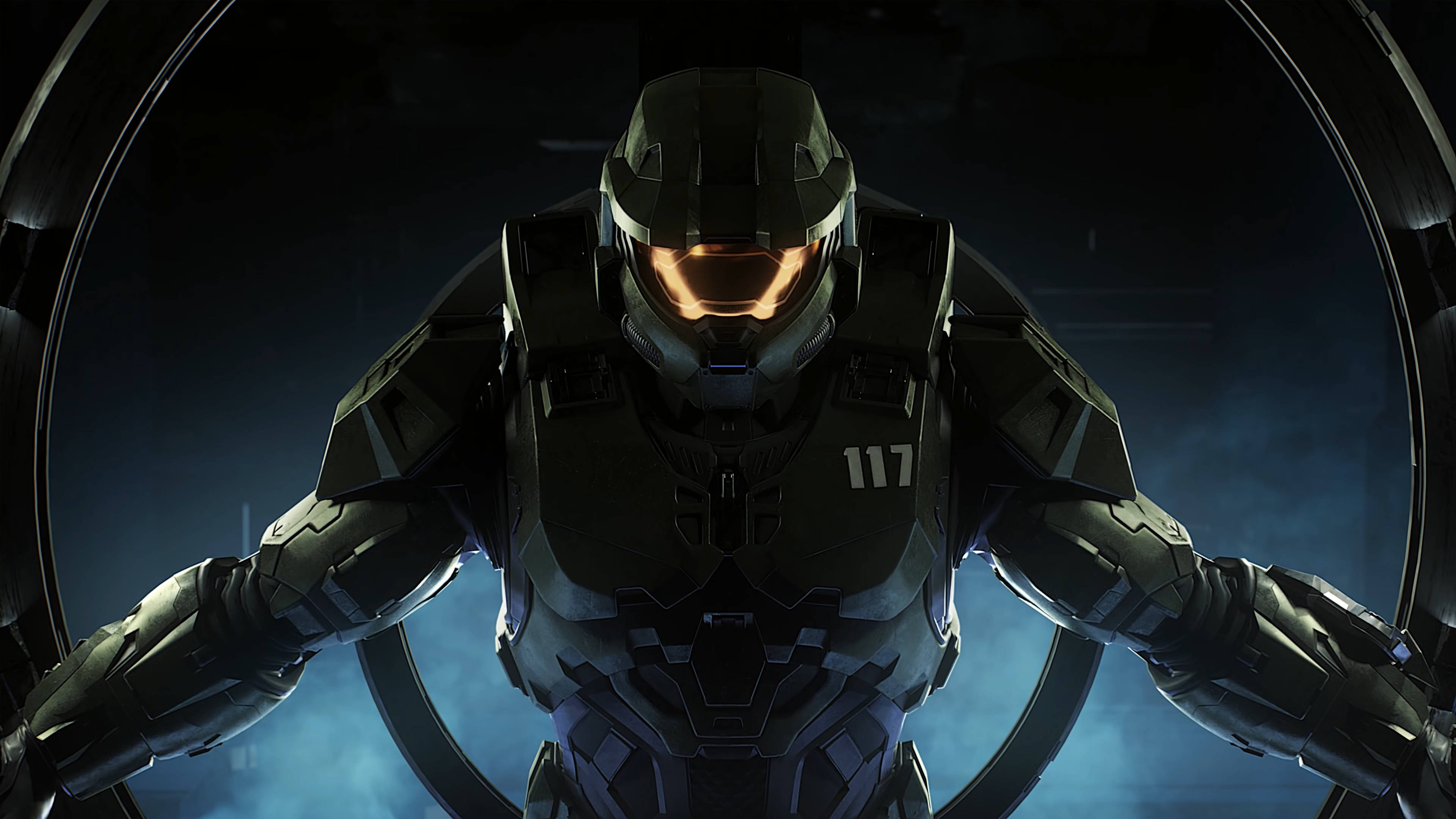 Master Chief 桌布 壁紙 — 一名身穿深色盔甲、帶有發光橙色面罩的斯巴達戰士，在煙霧藍色背景的圓形門口威嚴地站立。