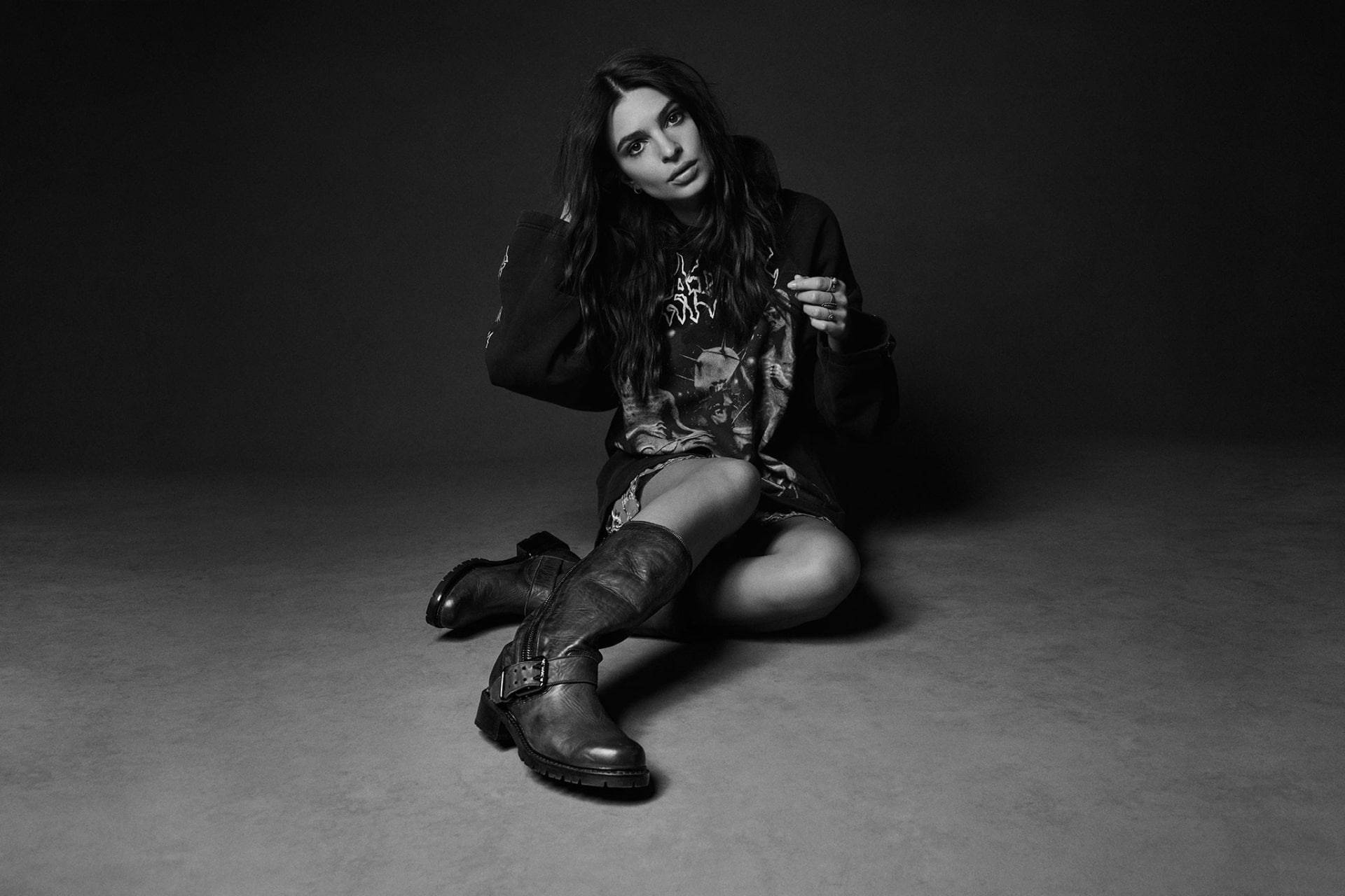 emily ratajkowski 桌布 壁紙 — 一名身穿深色衣服的女子坐在灰色地板上，拍攝一張氣氛憂鬱的黑白工作室肖像。