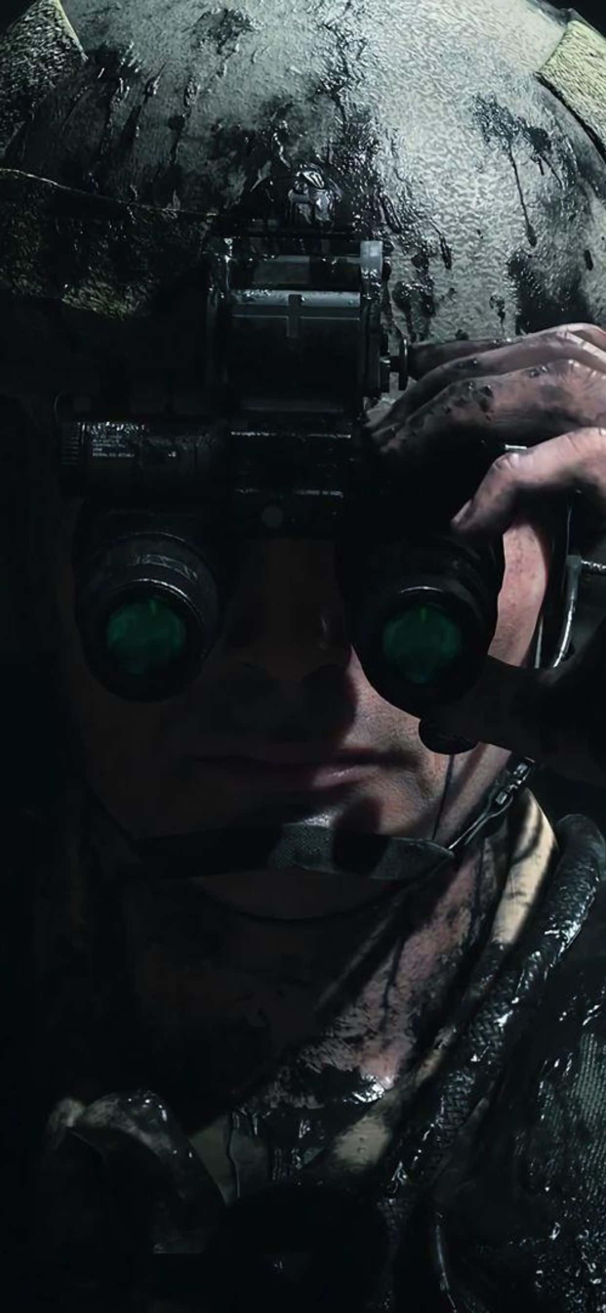 iPhone Xs Max Death Stranding 桌布 壁紙 — 一名身穿深色裝備的士兵在昏暗的戰場環境中透過發光的綠色夜視鏡凝視。