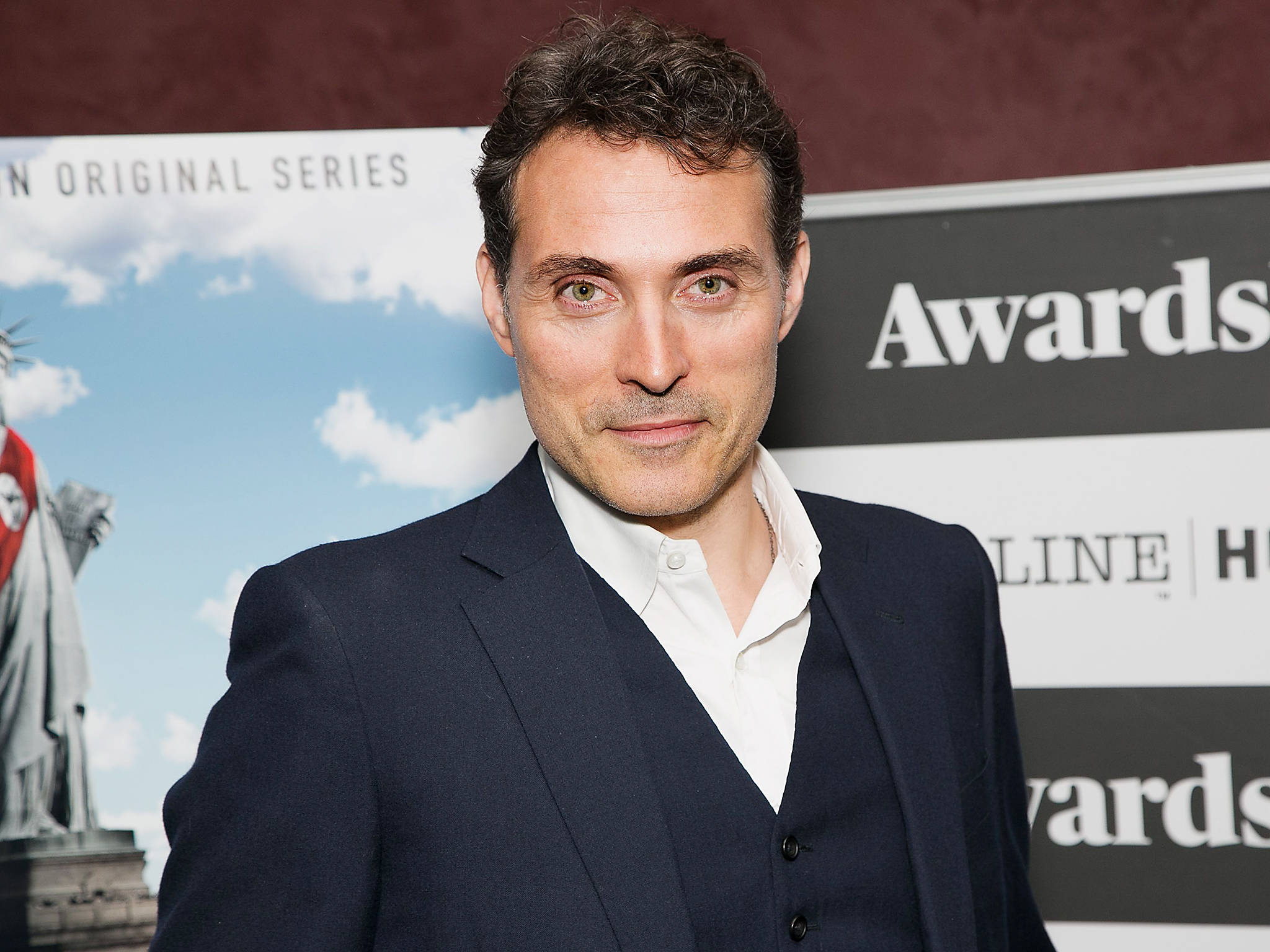 actor 桌布 壁紙 — 一名身穿深色西裝和白色襯衫的男子在頒獎典禮上自信地擺姿勢，背景是自由女神像。