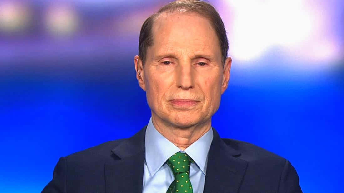 Celebrity 桌布 壁紙 — 一名身穿深色西裝和綠色圓點領帶的男子，在模糊的藍色工作室背景前的特寫。