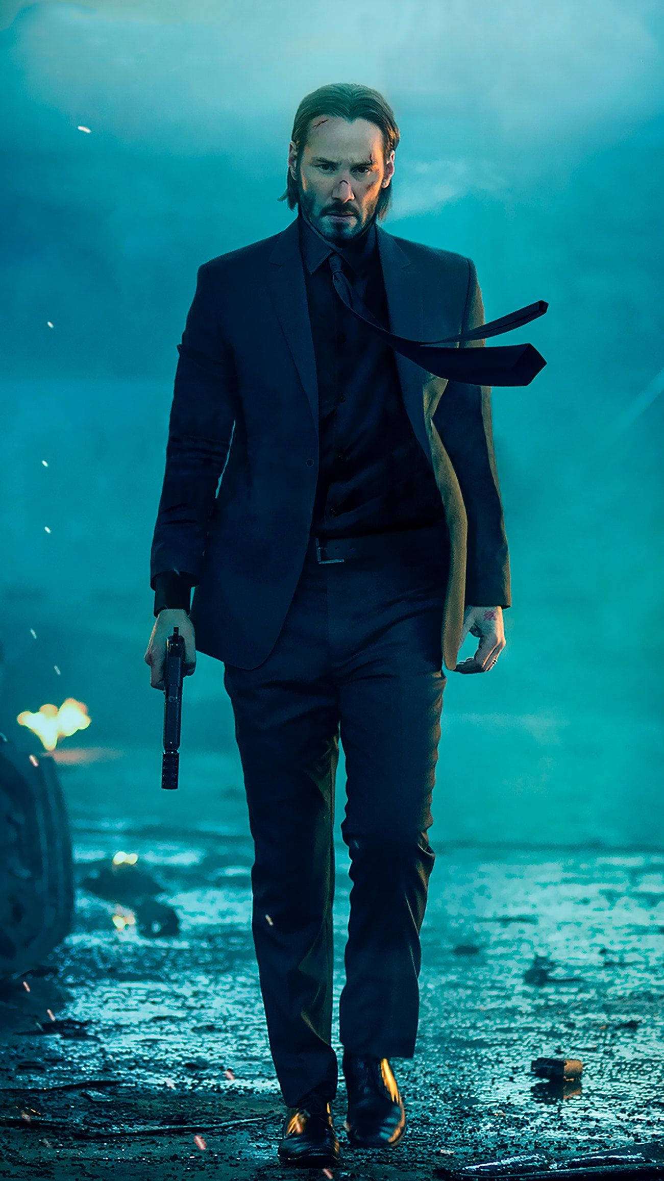 John Wick 桌布 壁紙 — 一名身穿深色西裝的男子，手持槍枝，走過煙霧瀰漫、藍色燈光的城市廢墟。