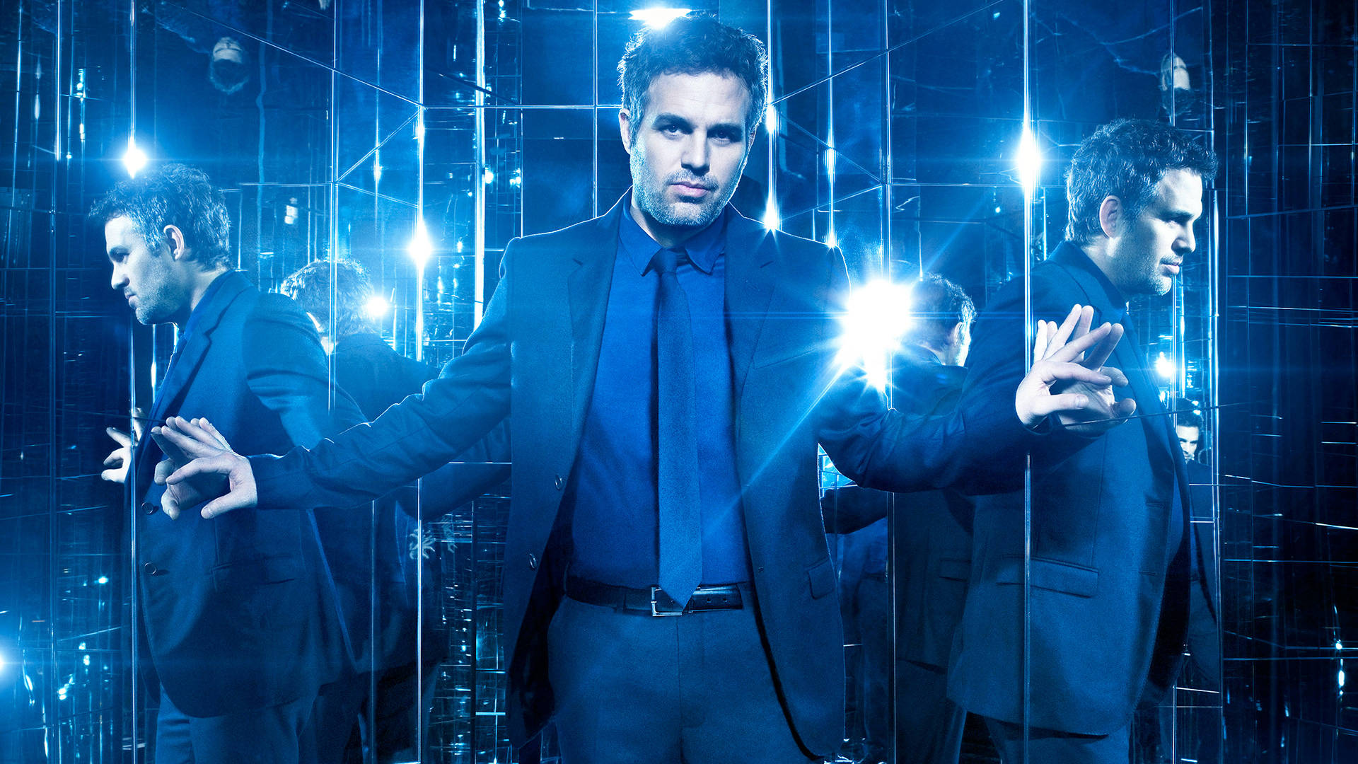 Mark Ruffalo 桌布 壁紙 — 一名身穿深色西裝的男子站在一個充滿電光藍色光芒及閃爍反射的鏡面房間中。