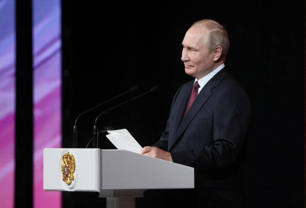 Leadership 桌布 壁紙 — 一名身穿深色西裝的男子站在帶有金色徽章的白色講台上，在舞台燈光下對著黑暗背景發表演講。
