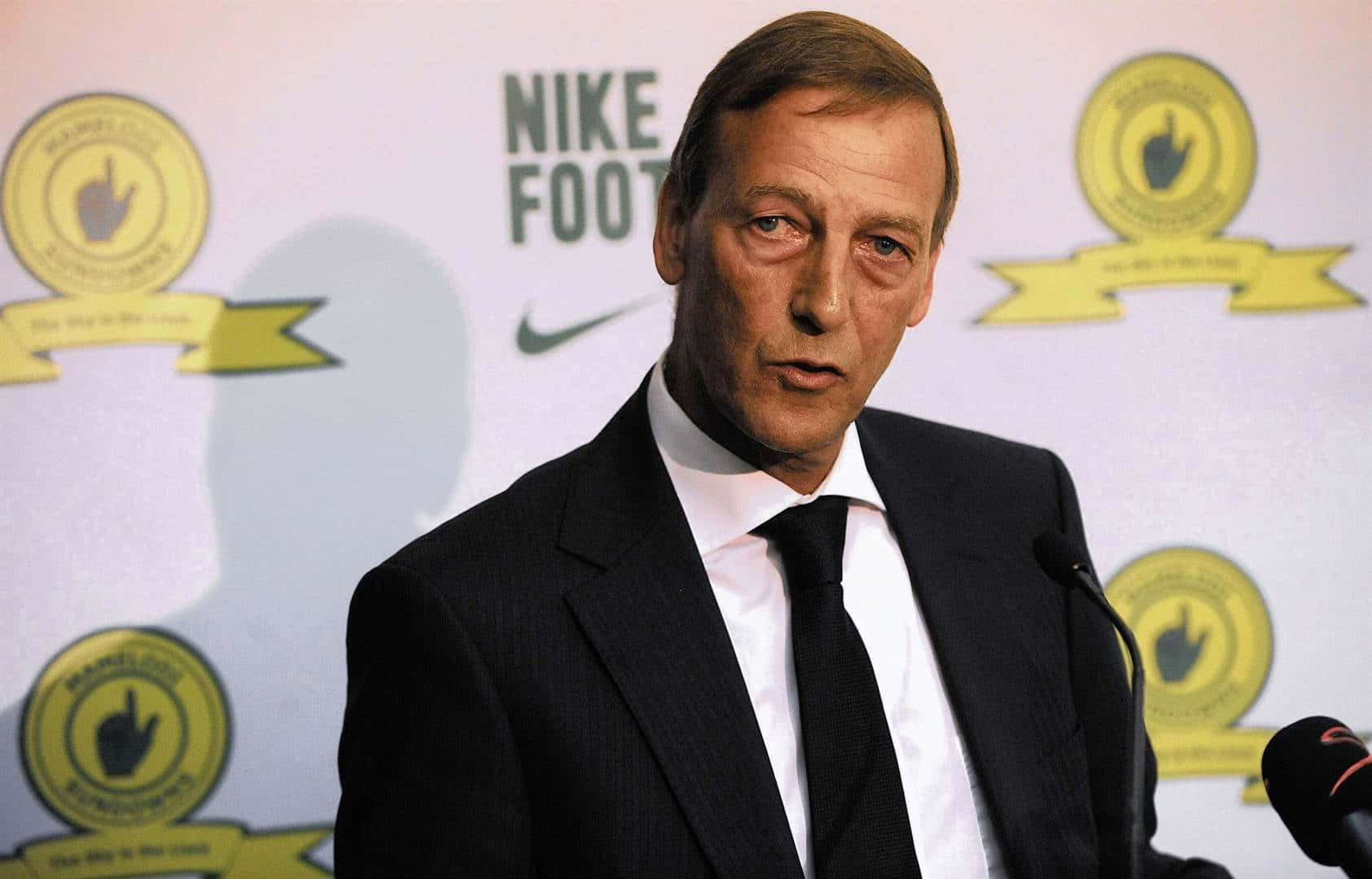 Netherlands 桌布 壁紙 — 一名身穿深色西裝的男子站在麥克風前，背景是Nike Football標誌和金色徽章。