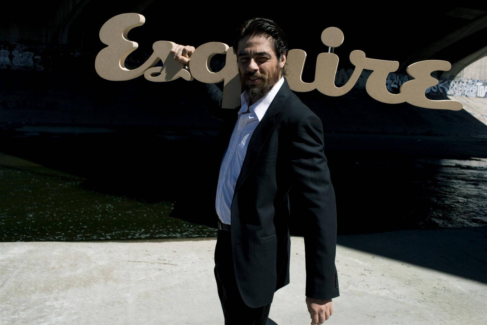 Celebrity 桌布 壁紙 — 一名身穿深色西裝的男子自信地站在一個大型 Esquire 標誌下，背景有塗鴉牆壁和水面。