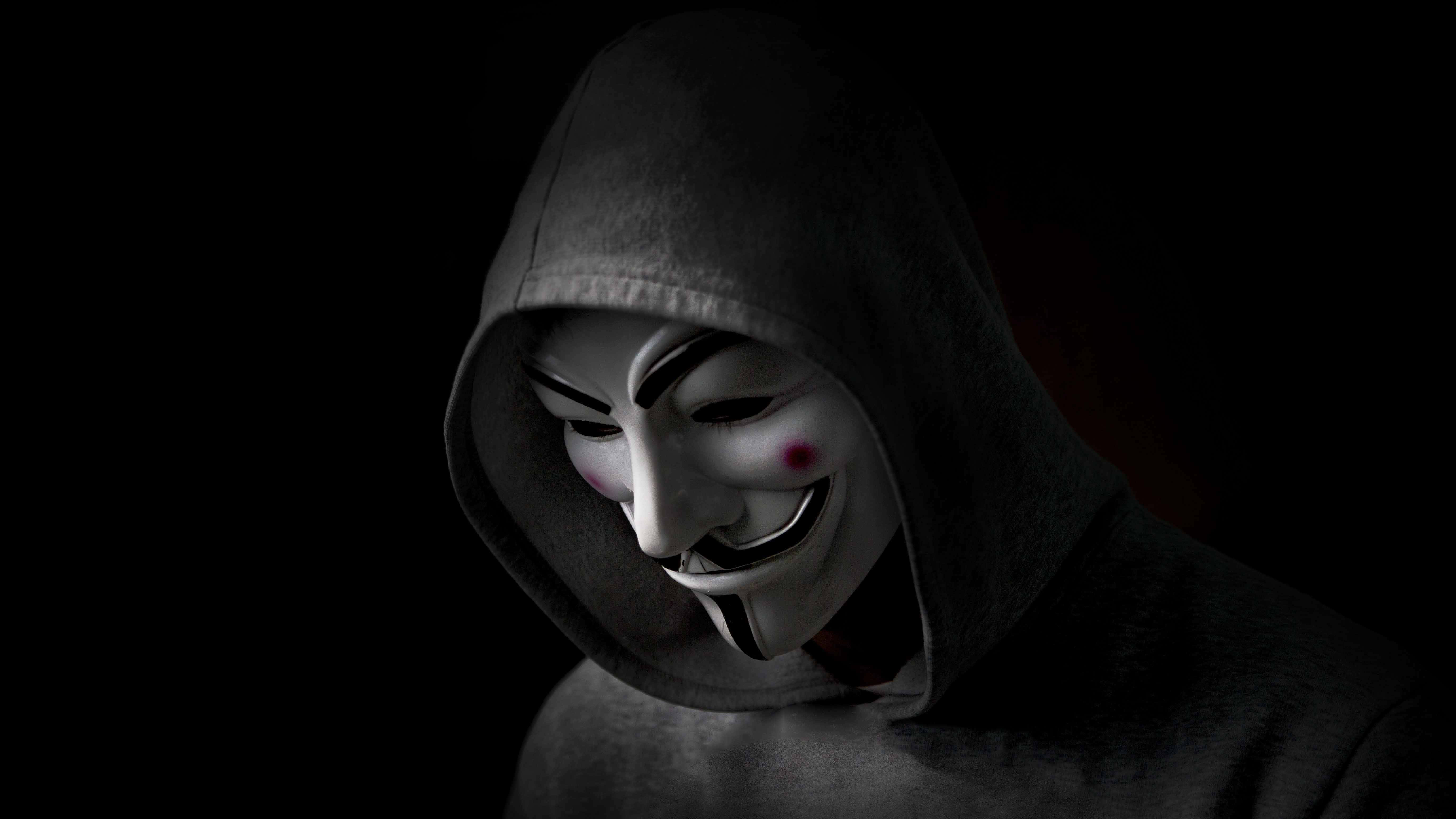 Mask 桌布 壁紙 — 一名身穿深色連帽衫的人，在黑色背景前戴著白色蓋伊·福克斯面具，臉頰為紅色。
