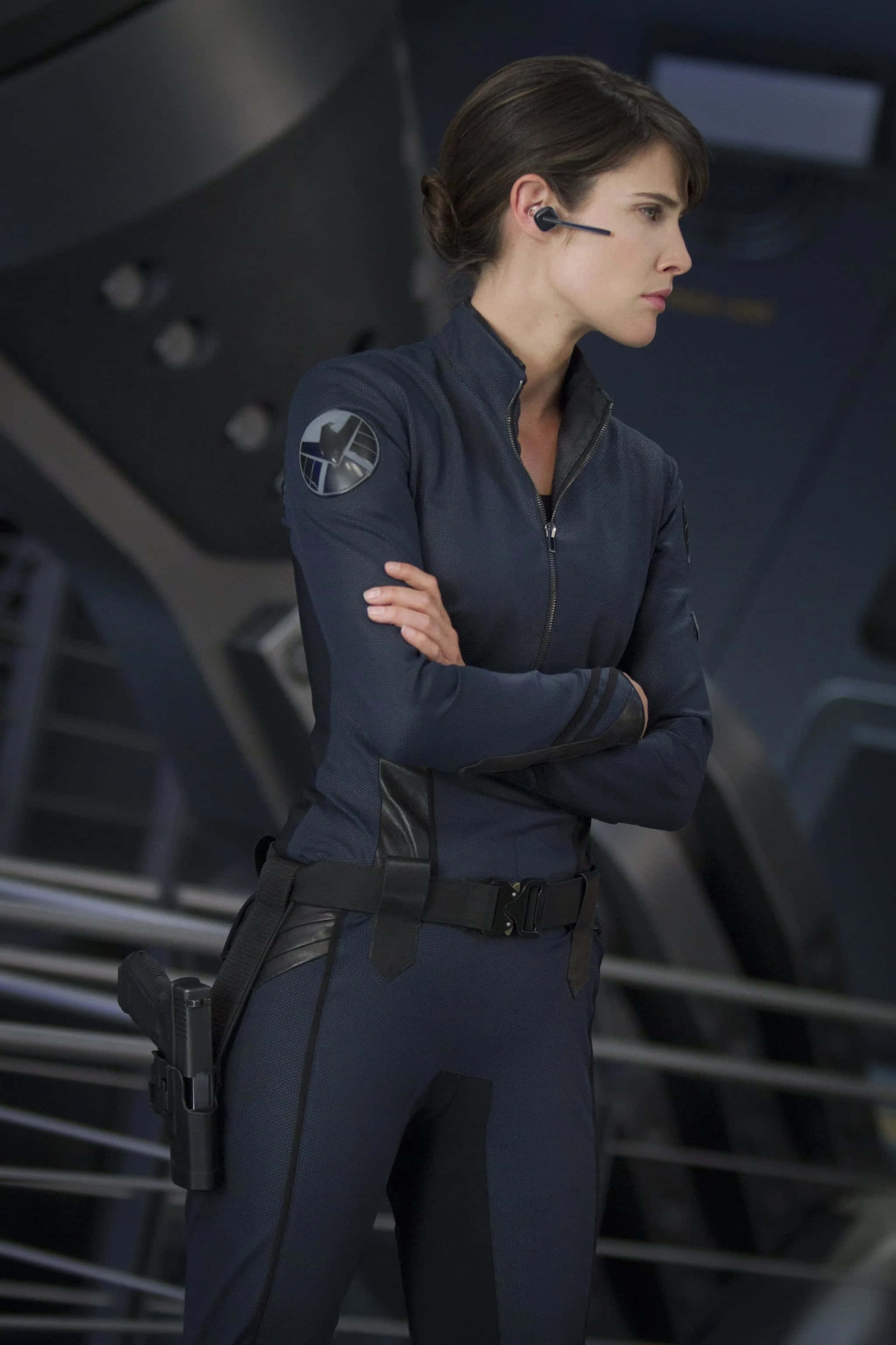 Maria Hill 桌布 壁紙 — 一名身穿深藍色戰術服的女性，在未來風格的太空船走廊中交叉雙臂站立。