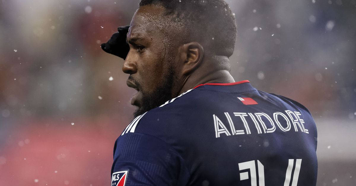 足球 桌布 壁紙 — 一名身穿深藍色球衣、背後印有「ALTIDORE」和11號的足球運動員，在飄雪中帶著專注的表情站立。