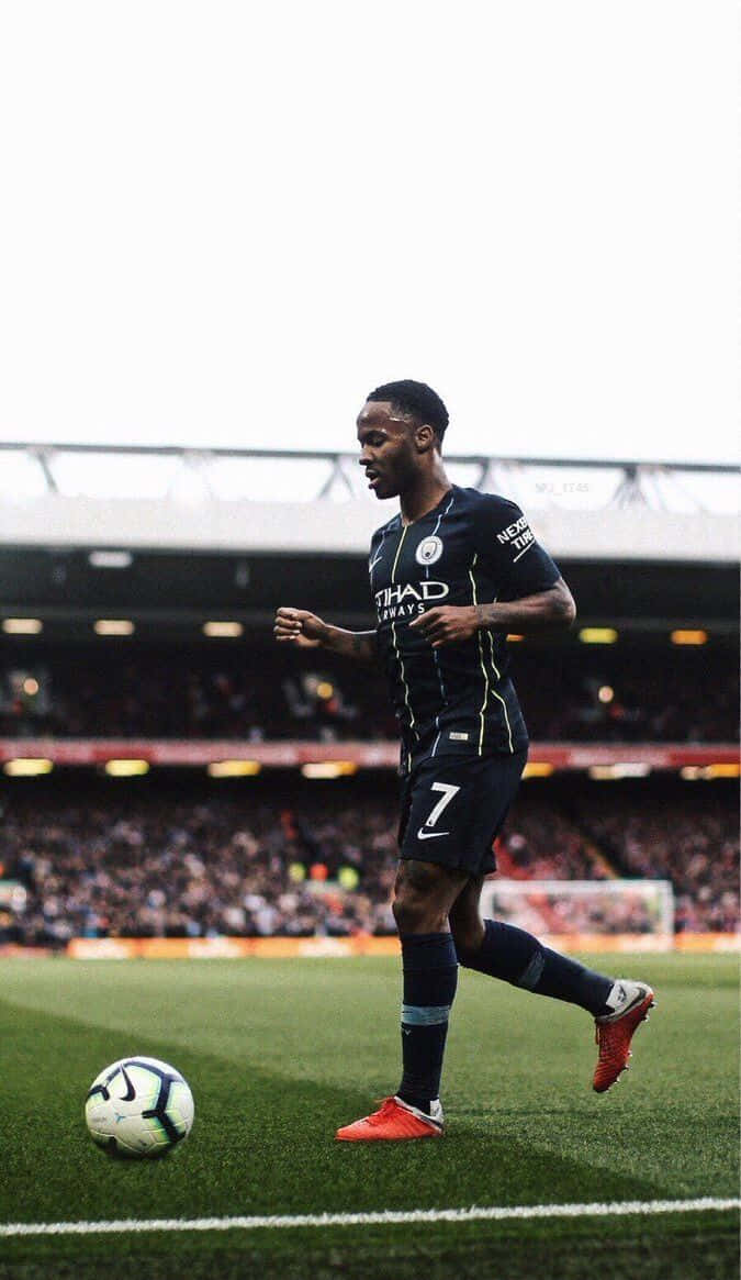 Sterling 桌布 壁紙 — 一名身穿深藍色球衣、背號7號的足球運動員在球場燈光下於綠色草地上盤帶白色足球。
