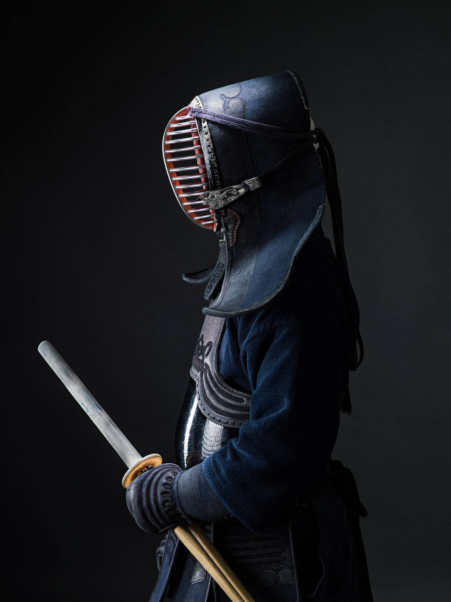 運動 桌布 壁紙 — 一名身穿深藍色盔甲的劍士側身站立，手持武士刀，背景為黑色。