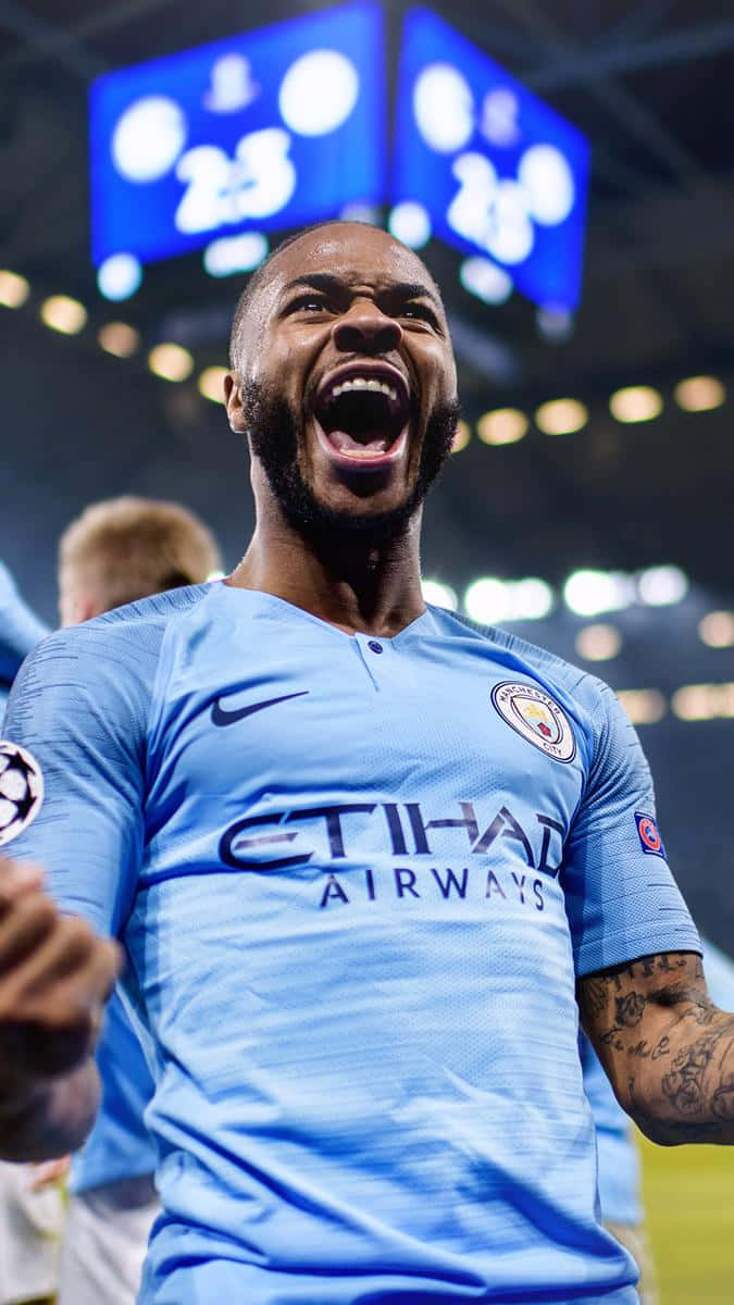 Sterling 桌布 壁紙 — 一名身穿淺藍色曼城球衣的足球運動員在燈光璀璨、座無虛席的球場中高舉雙臂，發出勝利的怒吼。