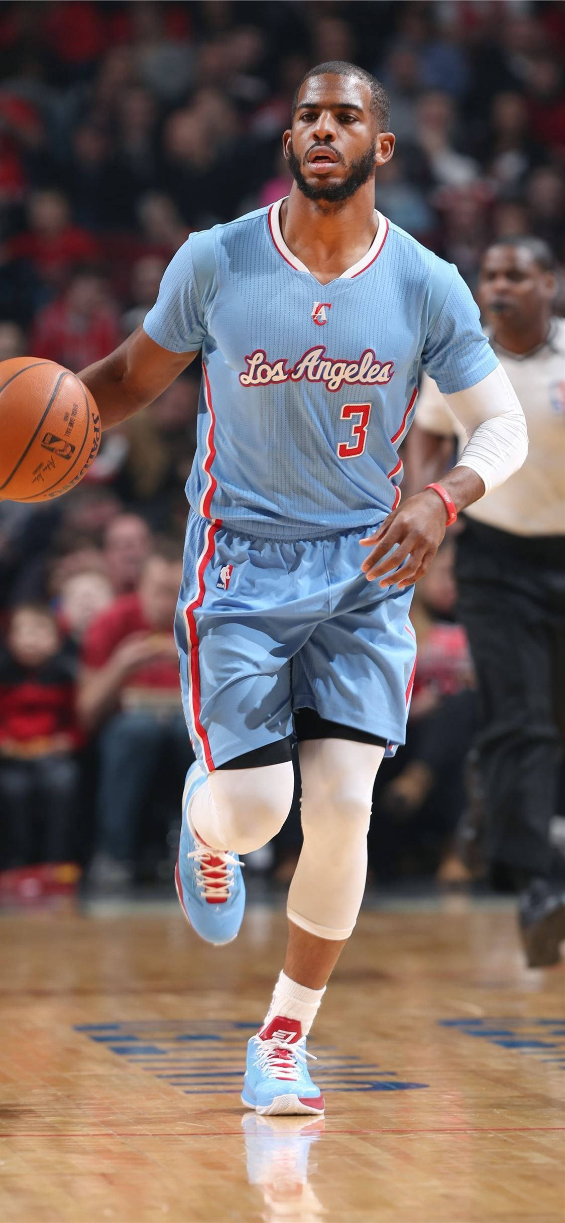 Chris Paul 桌布 壁紙 — 一名身穿淺藍色洛杉磯球衣的籃球運動員在拋光木地板上運球，背景有模糊的觀眾。