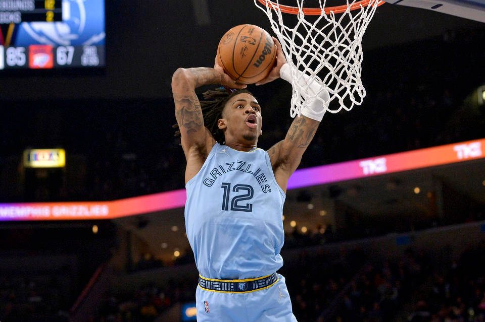 籃球運動員在擠滿觀眾的場館中執行強力灌籃。 — Ja Morant 動圖 壁紙