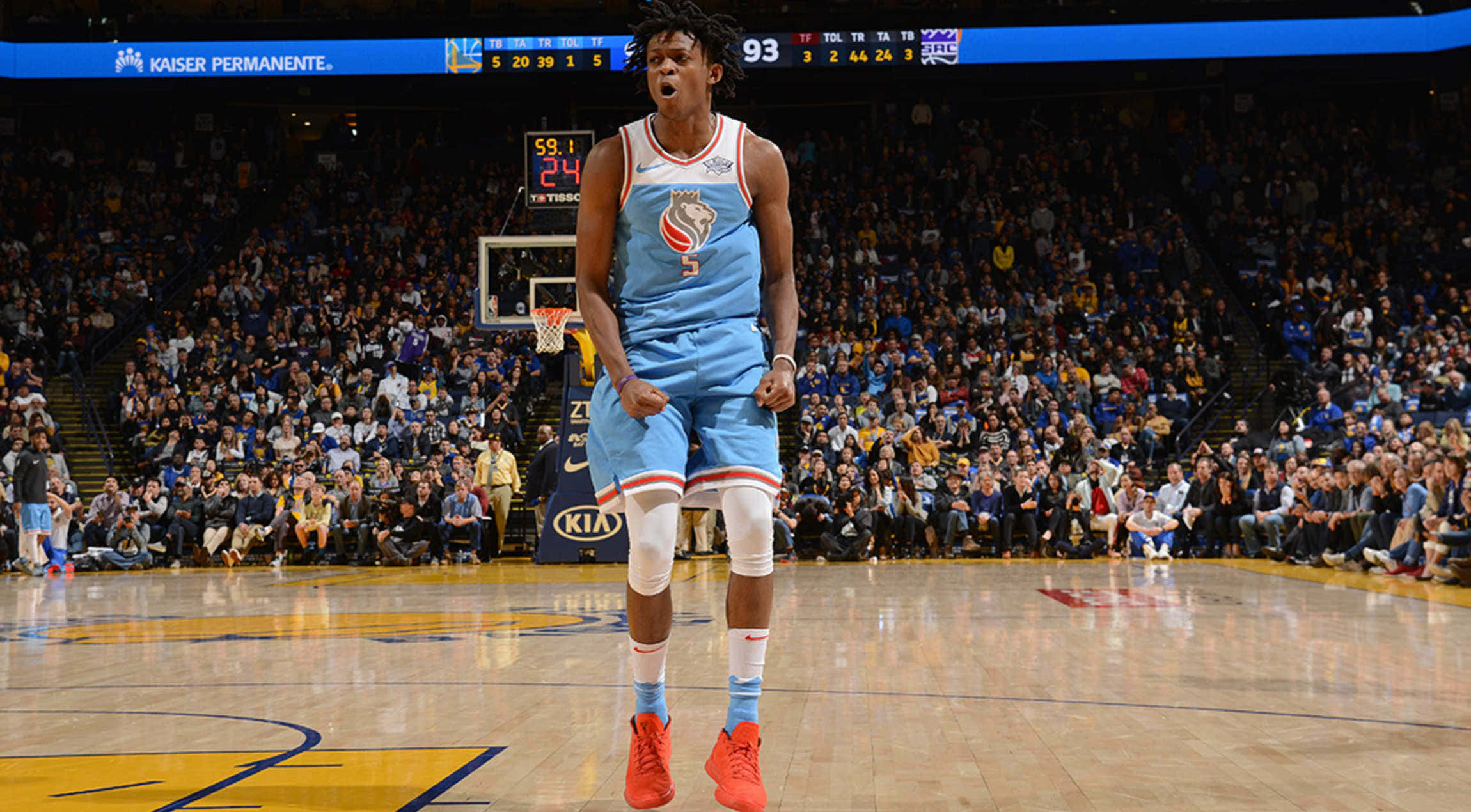 NBA 桌布 壁紙 — 一名身穿淺藍色球衣和紅色球鞋的籃球運動員，在明亮的燈光下，於座無虛席的體育館比賽中，在中場慶祝。