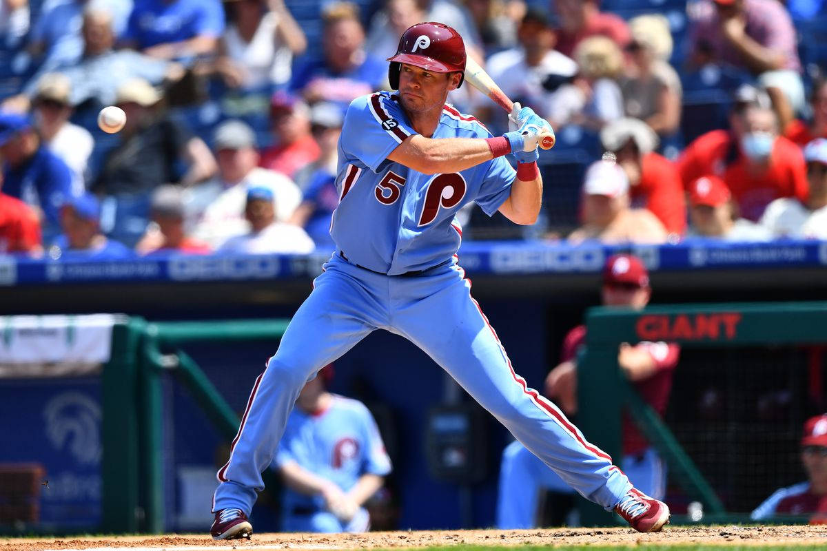 Phillies 桌布 壁紙 — 一名身穿淺藍色球衣的棒球運動員在陽光明媚的日間比賽中揮棒擊打白色球，背景有觀眾。