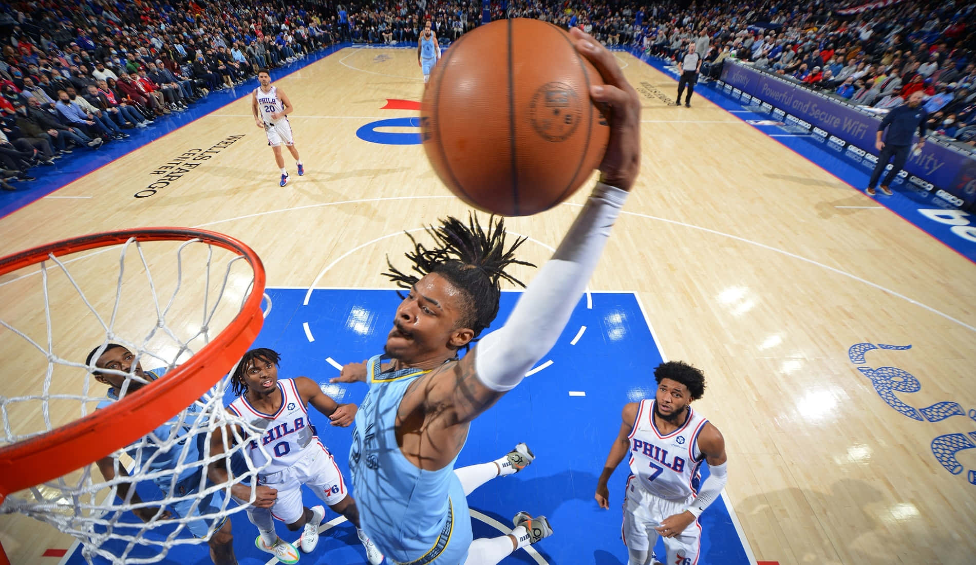 Ja Morant 動圖 桌布 壁紙 — 一名身穿淺藍色球衣的籃球運動員在防守球員從下方觀看時，以高度專注力灌籃。