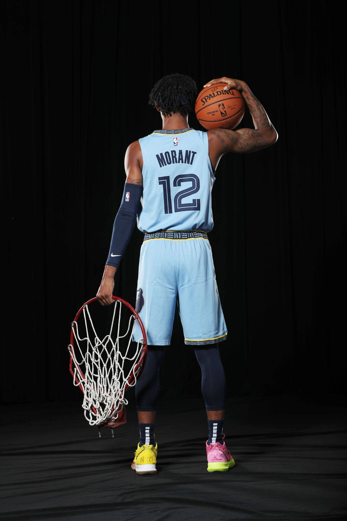 Grizzlies 桌布 壁紙 — 一名身穿淺藍色球衣的籃球運動員在黑色背景下拿著一個球和一個網。
