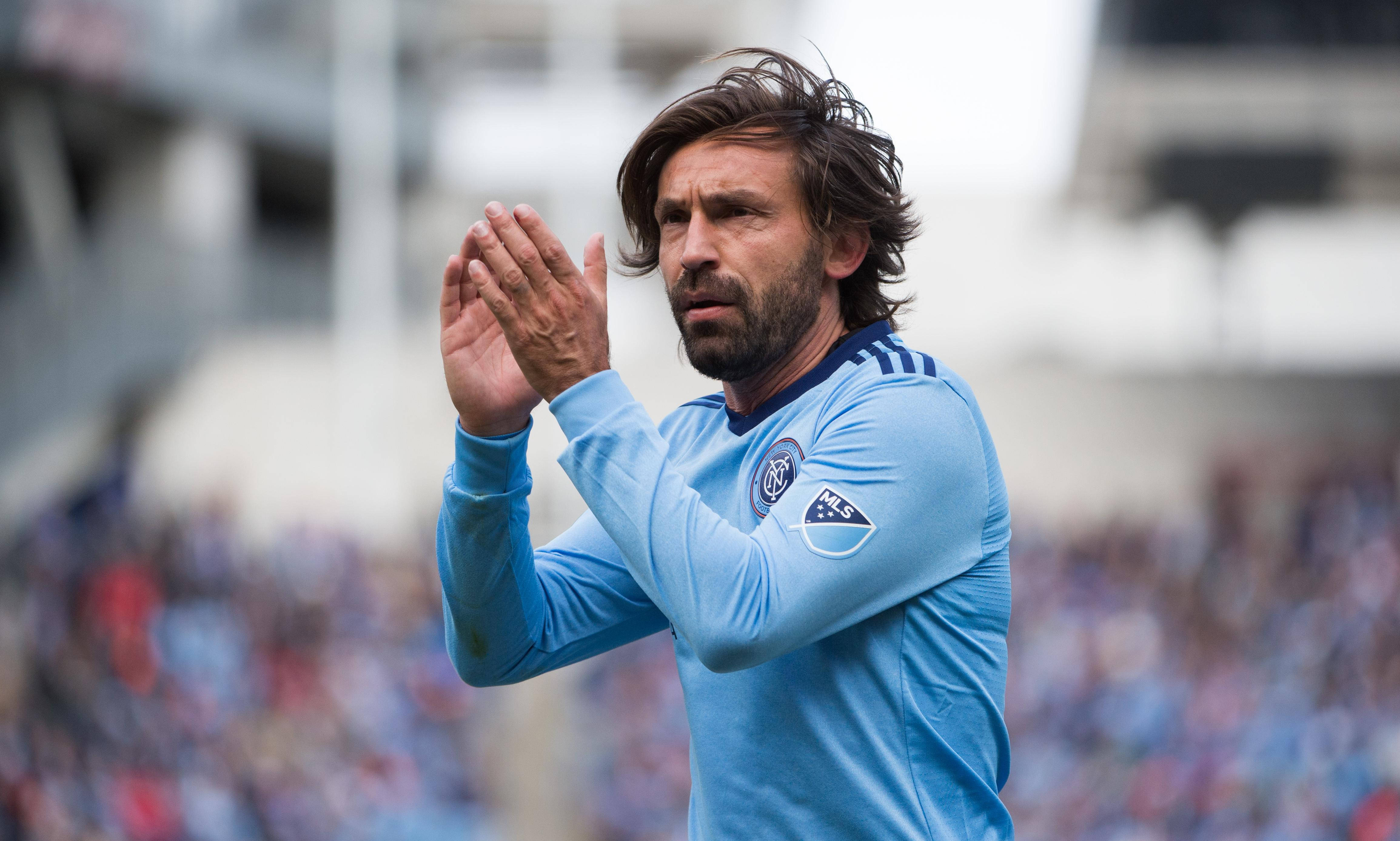 andrea pirlo 桌布 壁紙 — 一名身穿淺藍色球衣的足球員在球場上向前看並拍手。