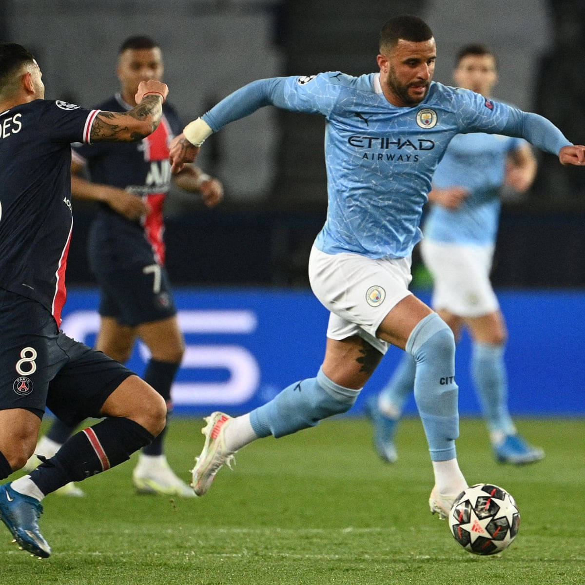 Kyle Walker 桌布 壁紙 — 一名身穿淺藍色球衣的足球員在綠色球場上盤球，同時受到身穿深海軍藍球衣的對手挑戰。