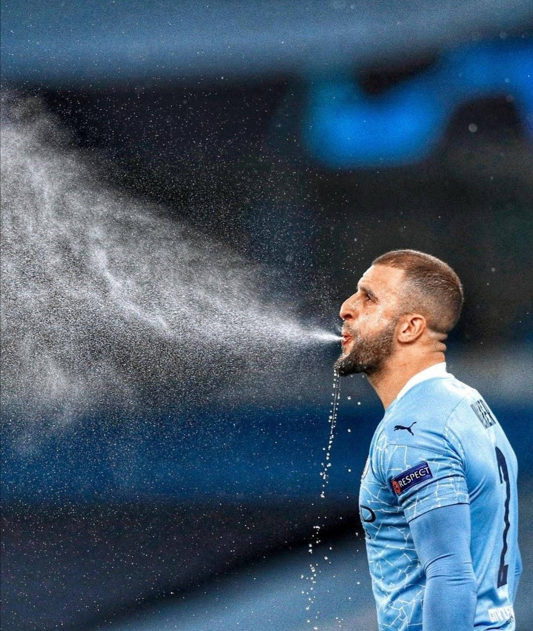 Kyle Walker 桌布 壁紙 — 一名身穿淺藍色球衣的足球員對著模糊的球場背景從口中噴出水蒸氣。