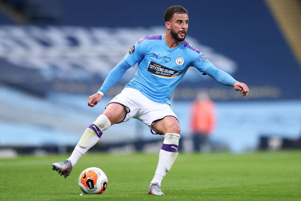 Kyle Walker 桌布 壁紙 — 一名身穿淺藍色球衣的足球運動員在體育場燈光下，在充滿活力的綠色球場上運球。